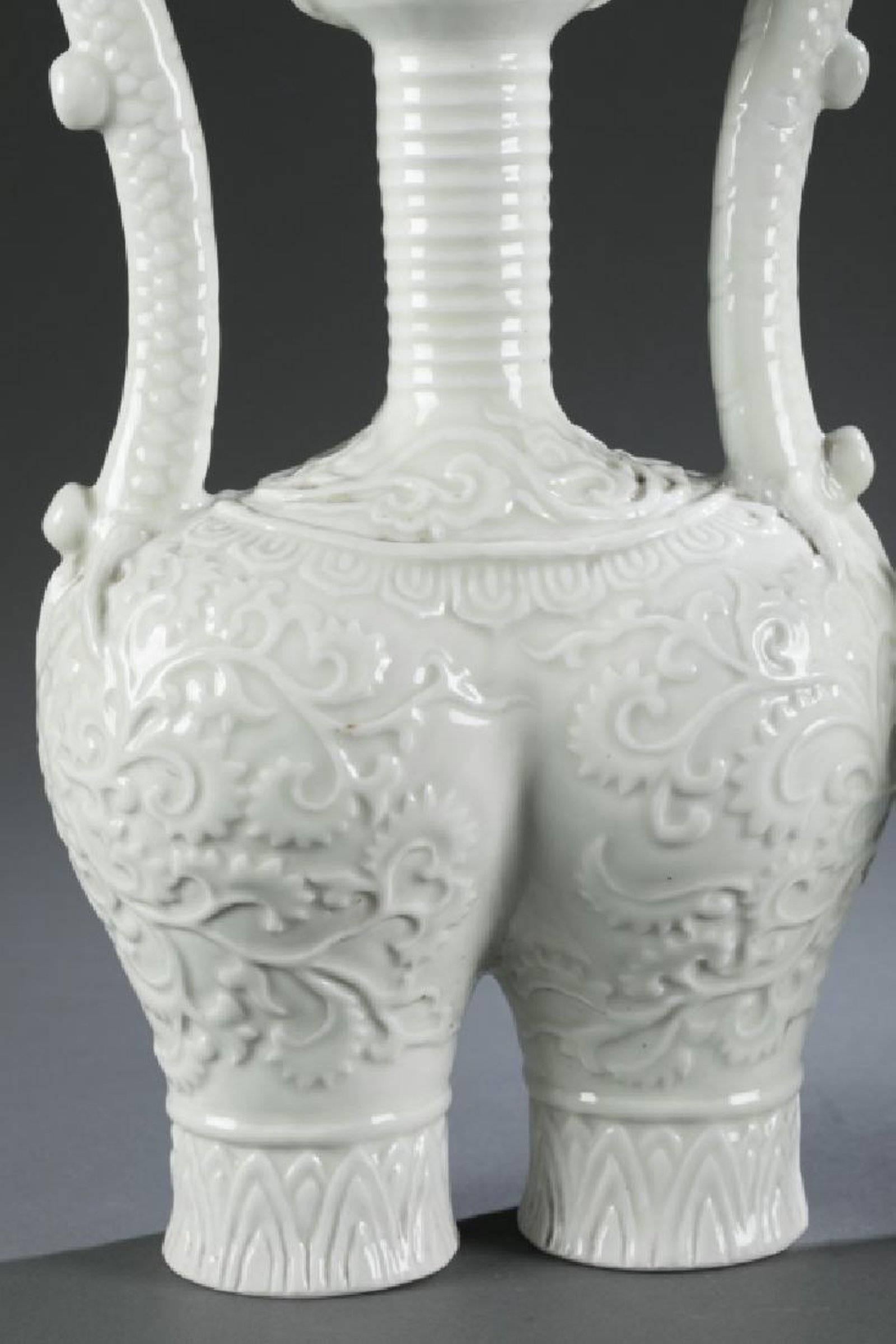 Highly unique of Blanc de Chine vessels with overall pattern of vines on the double base body with slim double dragon handles. 14 inches high. Sold individually.

 