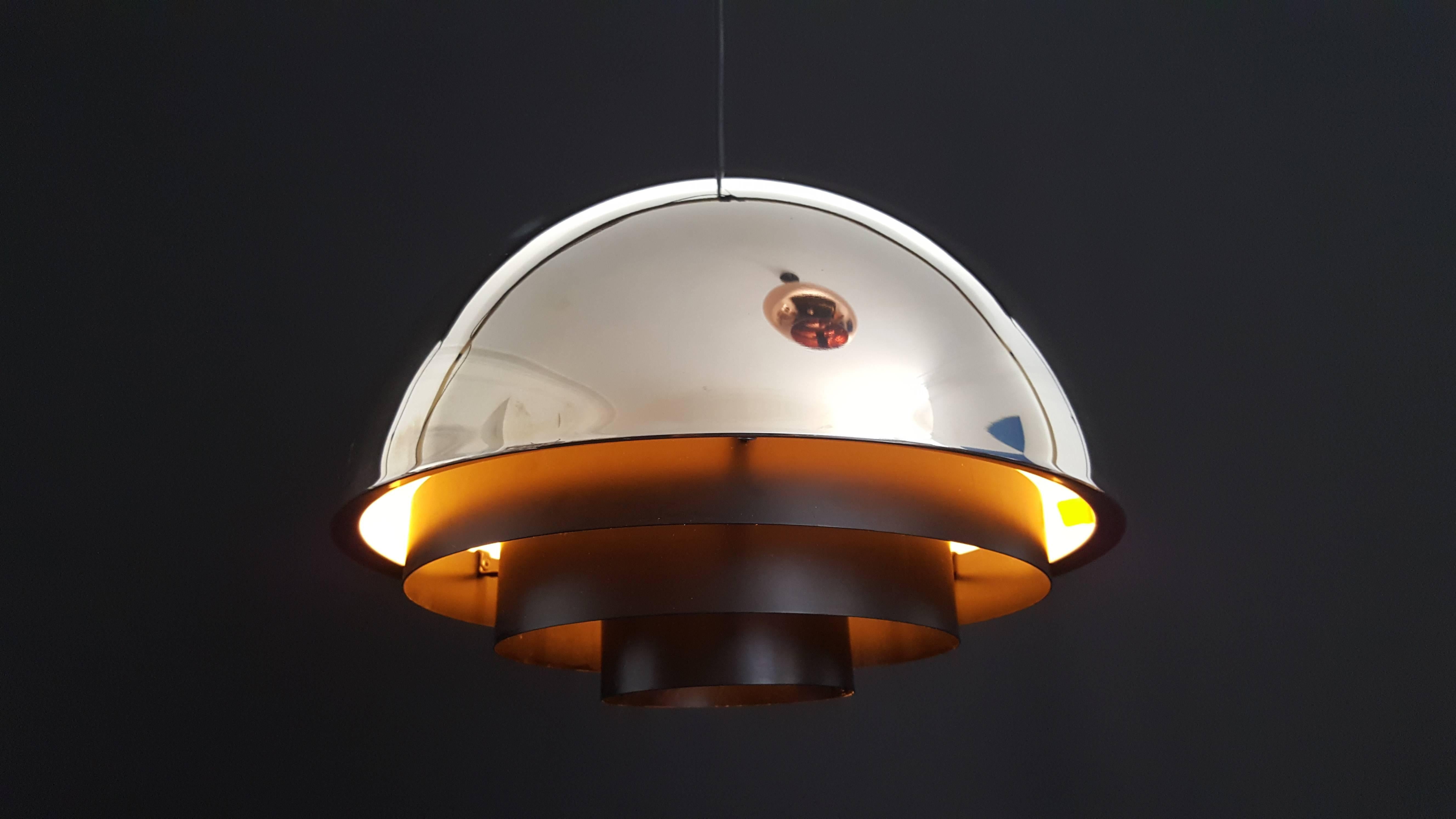 A Milieu pendant lamp designed by Jo Hammerborg in the early 1960s and manufactured by Fog & Mørup in Denmark.
 
The lamp is made from chrome with black metal graduated tiers and omits a glare-free light. 

In 1957 Jo Hammerborg became head