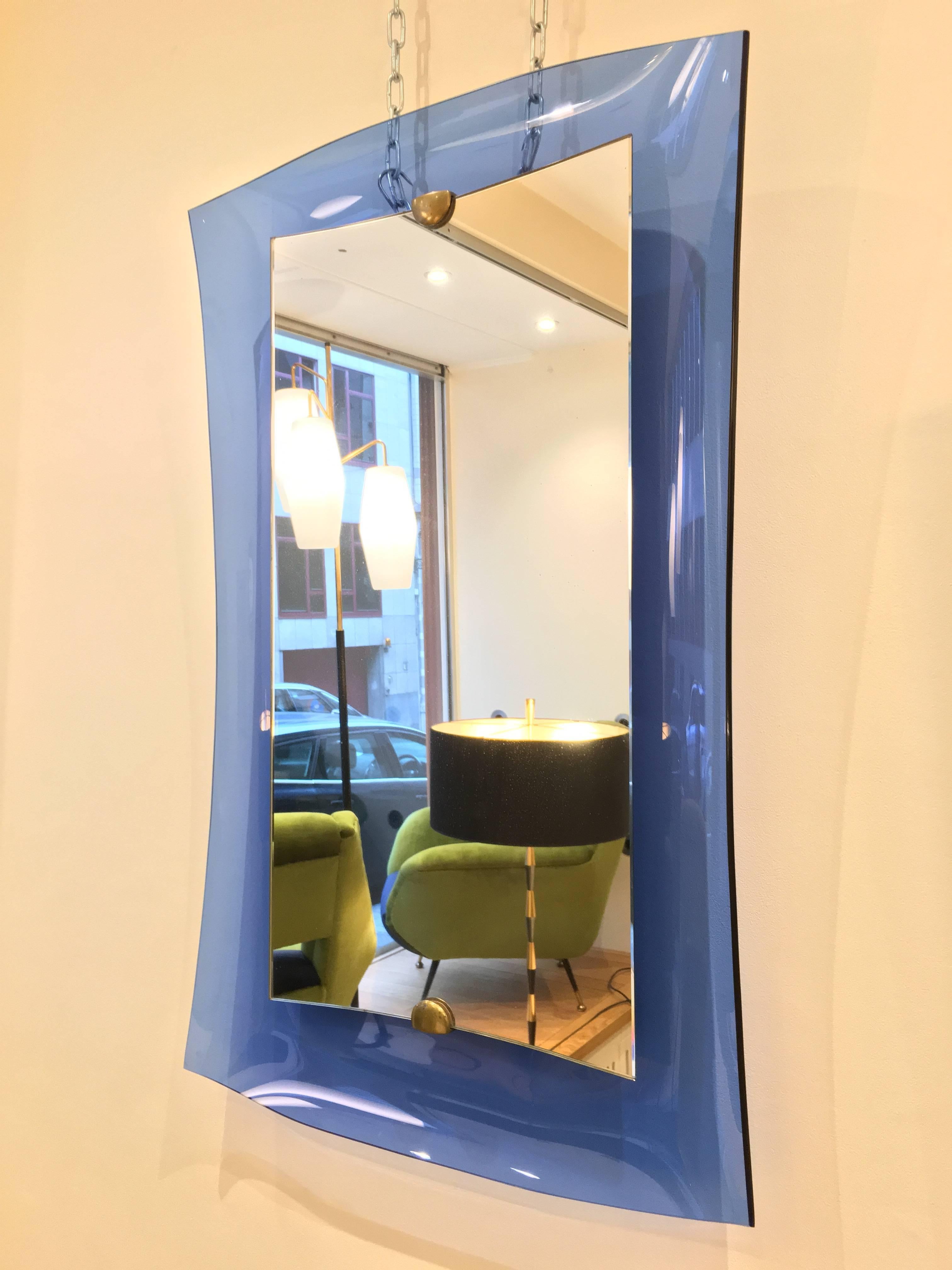 The blue color is quite rare, as is this type of mirror. The mirror is very interesting regarding its curves and concave shape. This gives a splendid decorative aspect to the piece. Equally, it is a technical prowess to achieve such a work in Glass.