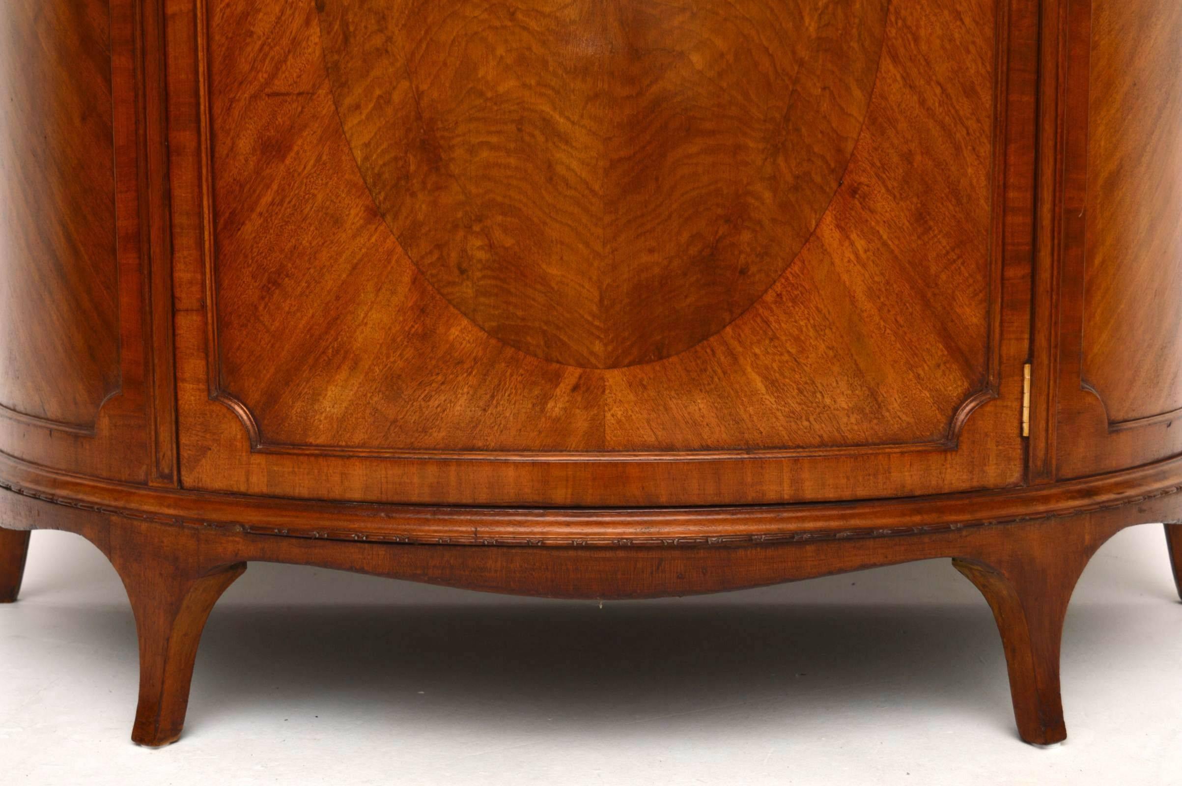 Impressive and practicable antique mahogany cabinet with a curved front. This piece is in good original condition, with a lovely mellow color and has loads of character. It has a solid mahogany top with a gadrooned edge. The middle door has an inset