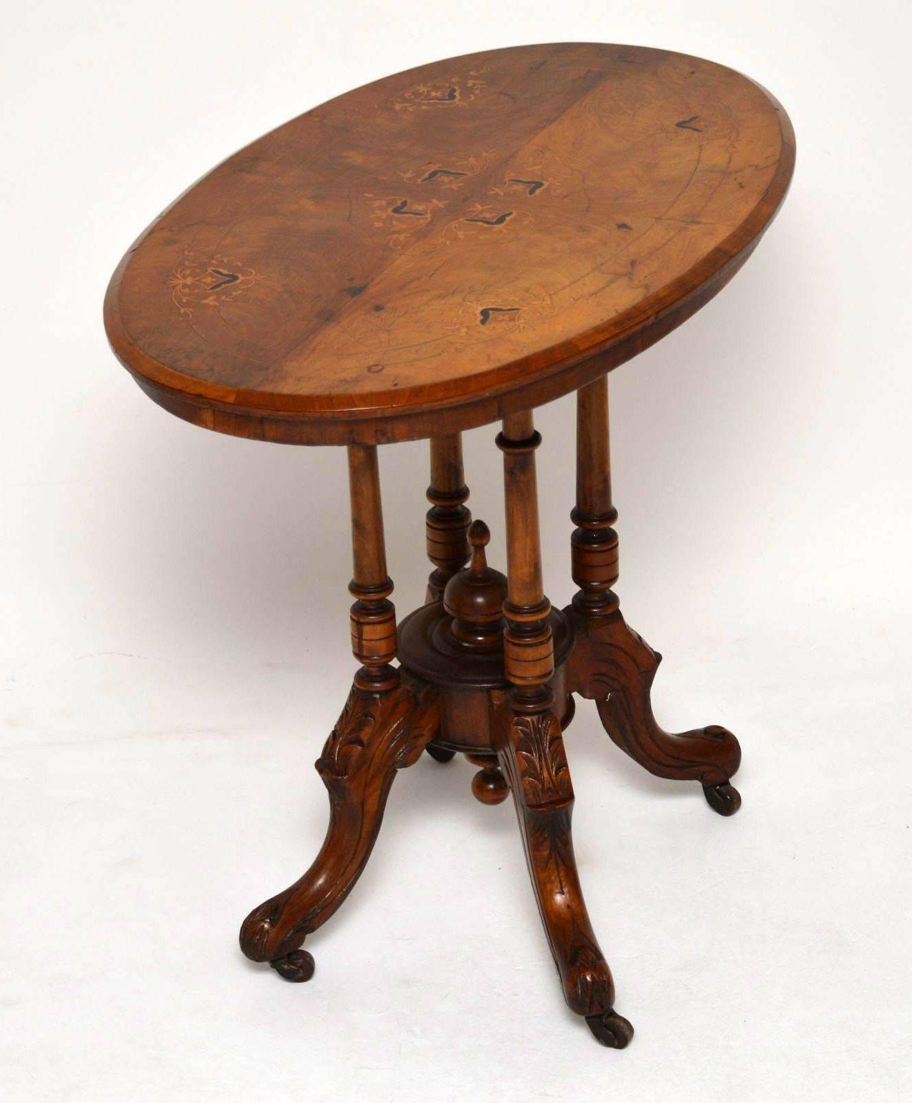 Antique Victorian walnut occasional table with an intricately inlaid top sitting on four turned supports that in turn sit on a carved quadruple legged base. This table is full of character and has a good warm color, plus it's in good condition. It