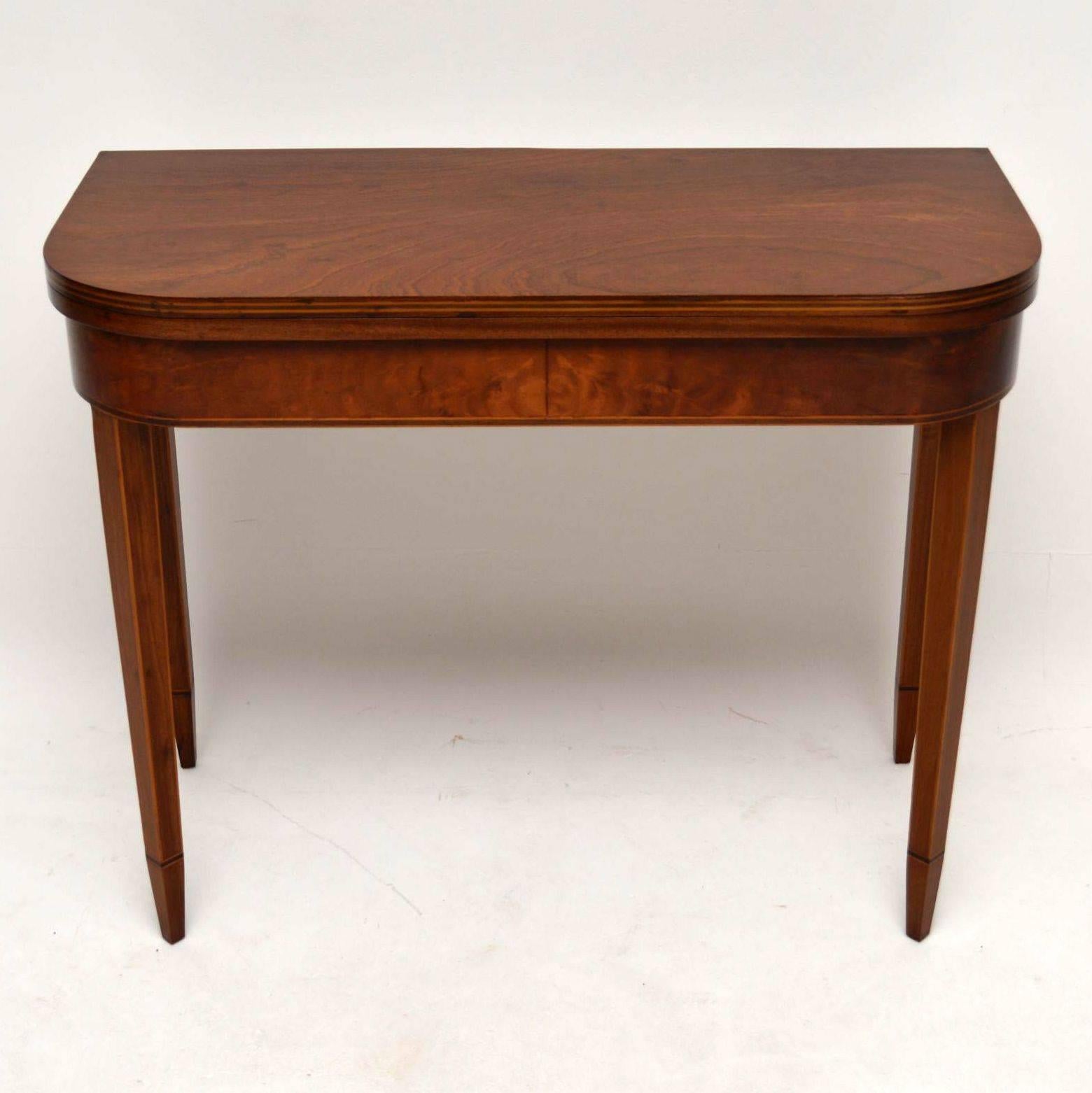 This card table is a good quality reproduction of a period George III piece and probably made around the 1950s period. It's mahogany with satinwood inlay and is in excellent condition having just been re-polished. The top opens up & is supported