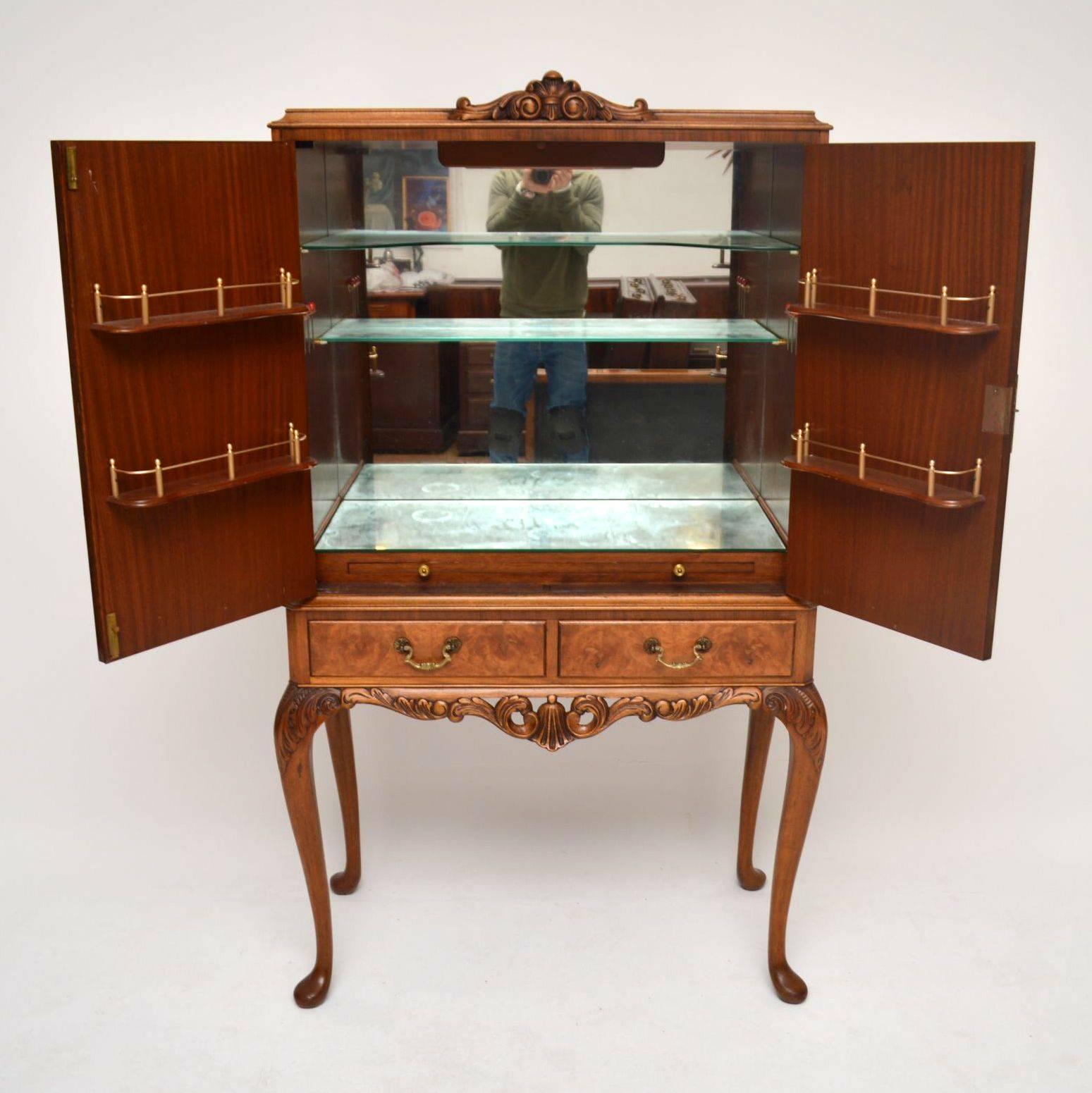 Antique walnut cocktail cabinet in excellent condition and dating from around the 1930s period. It's beautifully carved on the top, plus between and on the shaped legs. The two doors are burr walnut, with crossbanding and the drawers are burr walnut