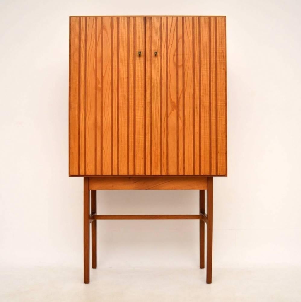 A very stylish and rare drinks cabinet made by GW Evans, this was probably designed by Ian Audley and it dates from circa 1950s. It's made from teak and another lighter wood, which we think is Elm. The condition is excellent for its age, with only