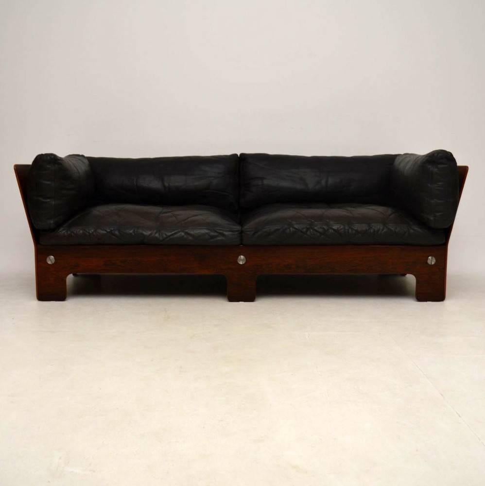 A stunning sofa in rosewood and leather, this dates from around the 1960s. The quality is amazing, we have had this stripped and re-polished to a very high standard, so the condition is superb. The black leather cushions are filled with feathers,