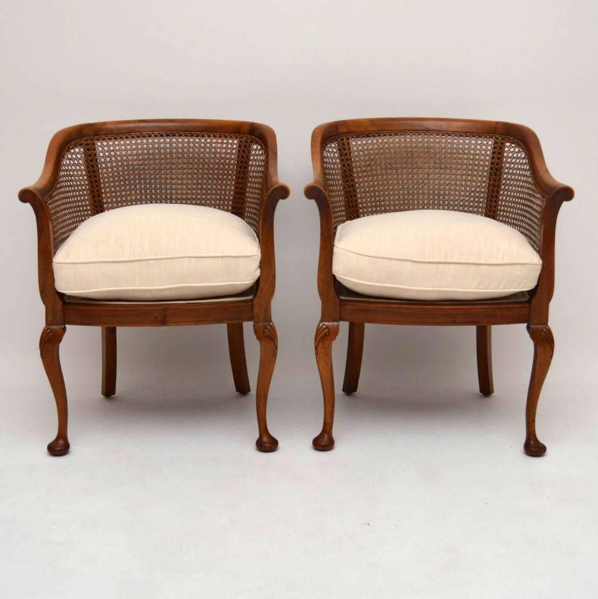 Pair of antique solid mahogany tub backed armchairs with original cane and carved Queen Anne legs. They are in excellent condition all-over and the wood has a nice warm color. They have just been re-upholstered in a cream fabric and the cushion are