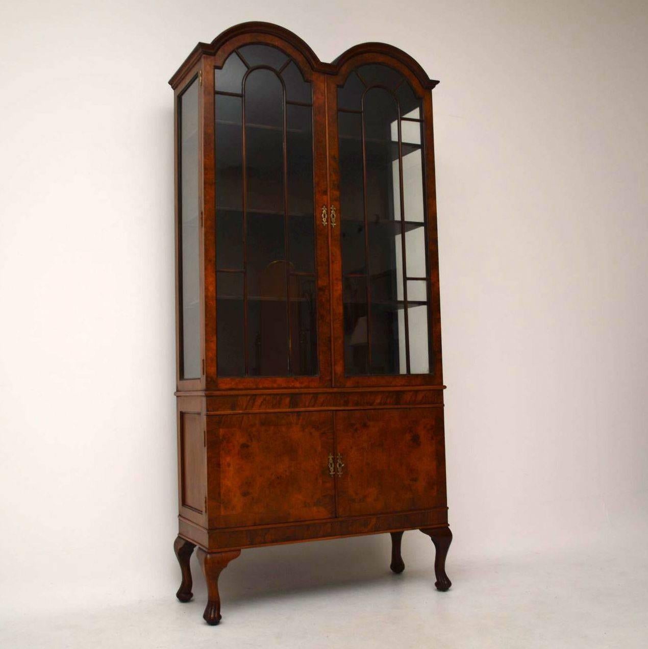 Impressive antique walnut display cabinet with a double arched top, two astral-glazed doors and two crossbanded burr walnut doors sitting on shaped Queen Anne legs. It’s in good condition with beautiful figuring in the woods and dates from circa