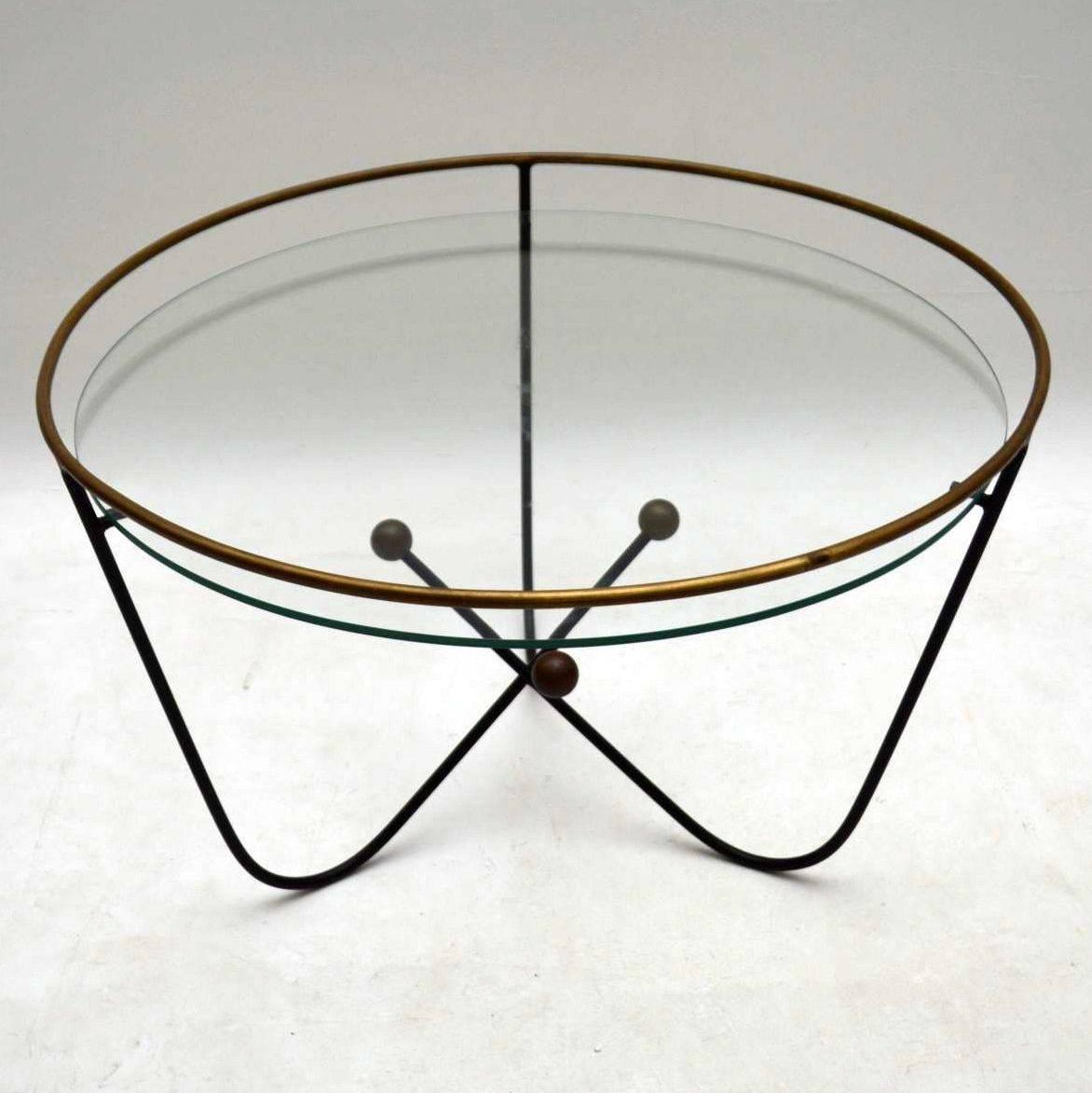 This stylish atomic style vintage coffee table was designed by Edward Ihnatowicz and was manufactured by Mars furniture in the 1950s. It has a black steel frame with a brass rim and three circular brass fixtures on the base. The frame has some