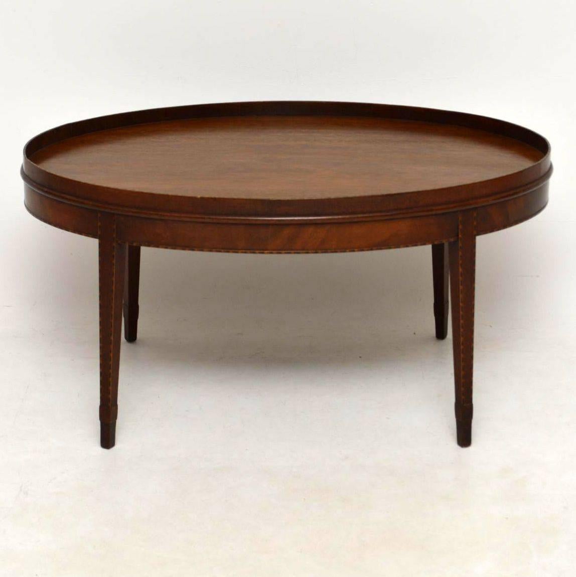 Very elegant antique mahogany oval top coffee table in good condition & dating from around the 1910-20’s period. It has a gallery around the top edge & the side border is flame mahogany. The tapered legs are angled outwards & have an added section