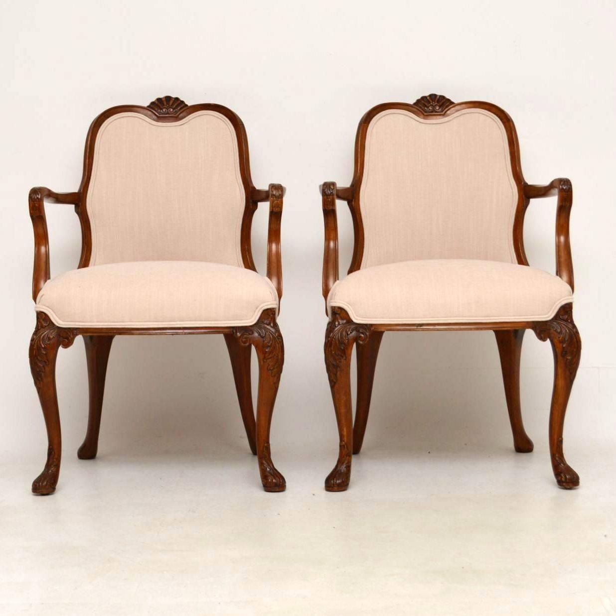 Pair of high quality solid walnut upholstered open armchairs in good condition and dating from the 1910s-1920s period. They are very much Queen Anne design with the typical carvings and the shepherds crook arms. They have shell carvings on the tops