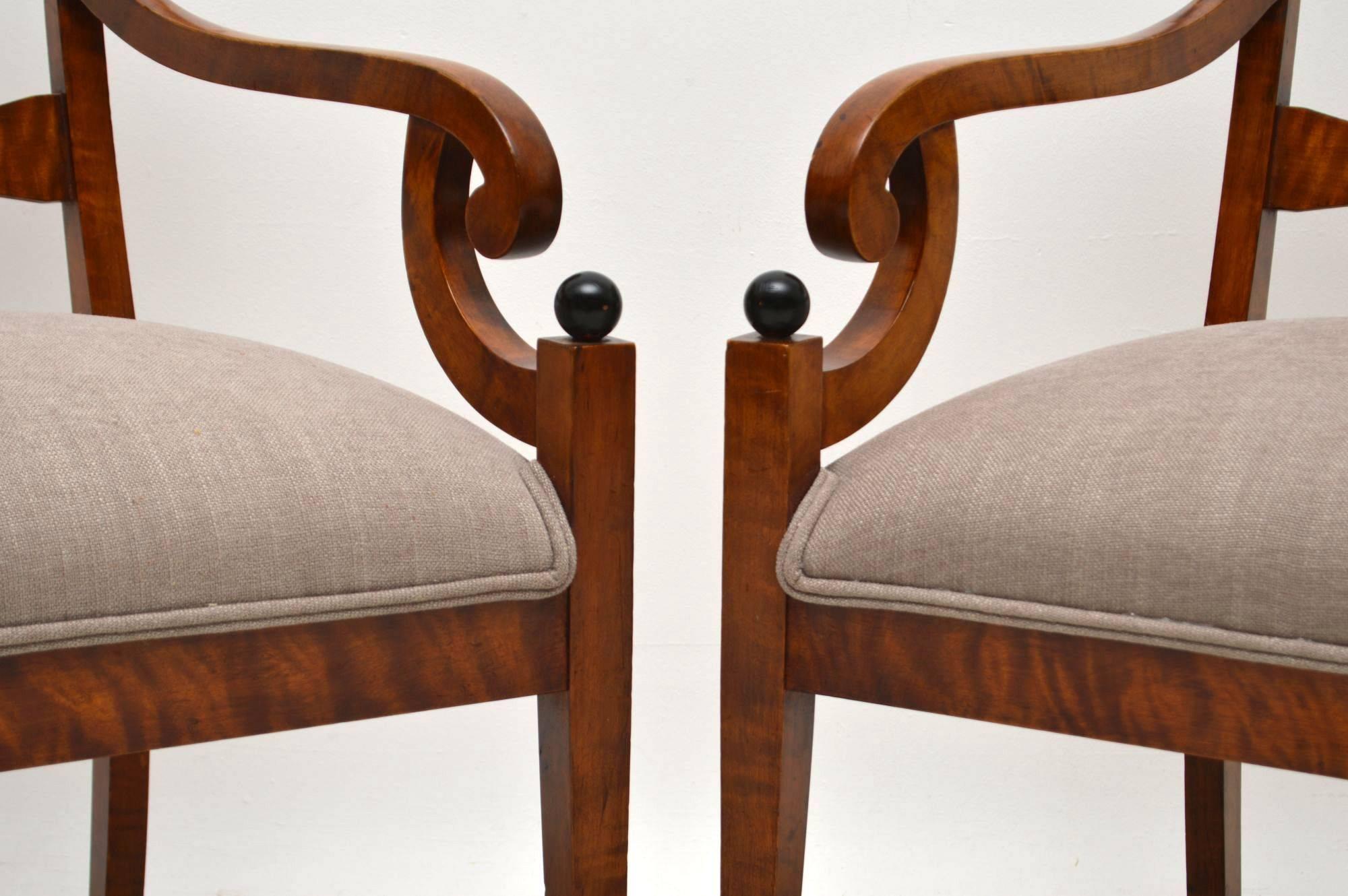 Stylish pair of antique Swedish Biedermeier armchairs in satin birch and newly re-upholstered. They have bold Trafalgar backs, scroll over arms, ebonized baubles and sit on Sabre legs. These chairs have quite large proportions and are very sturdy.
