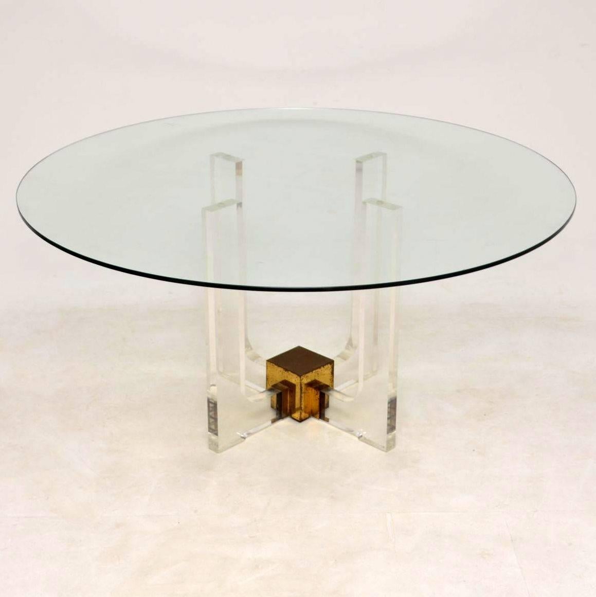 A stunning vintage dining table with a huge circular glass top and thick clear Lucite base this dates from the 1970s. The base has a brass block connecting the four supports, the brass has some surface wear and tarnishing seen in the images, the