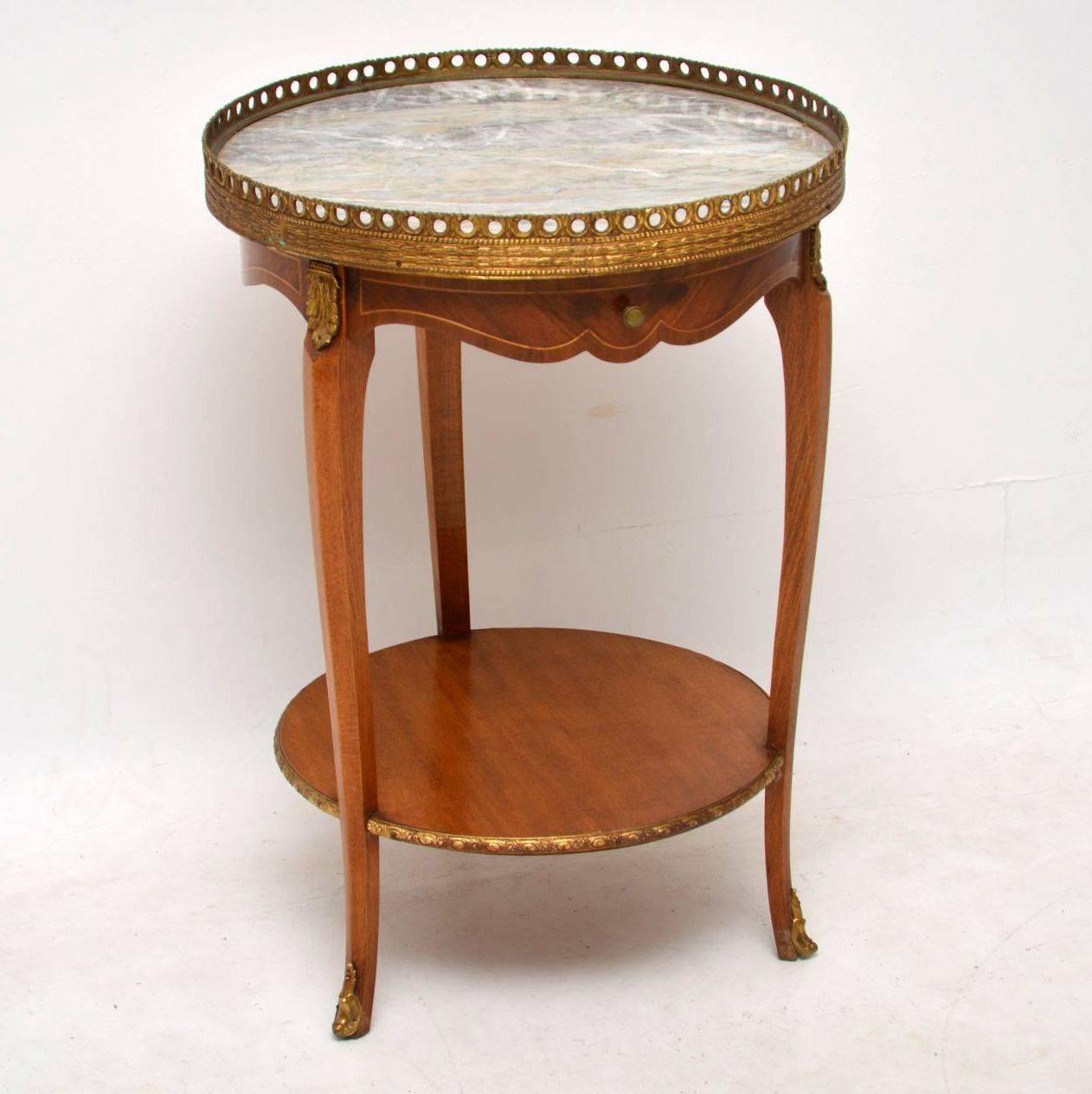 Small antique French marble-top side table in good condition and dating from around the 1910s-1920s period. The marble top is surrounded by a gilt metal gallery with a drawer below. The drawer and the rest of the shaped sides are kingwood with