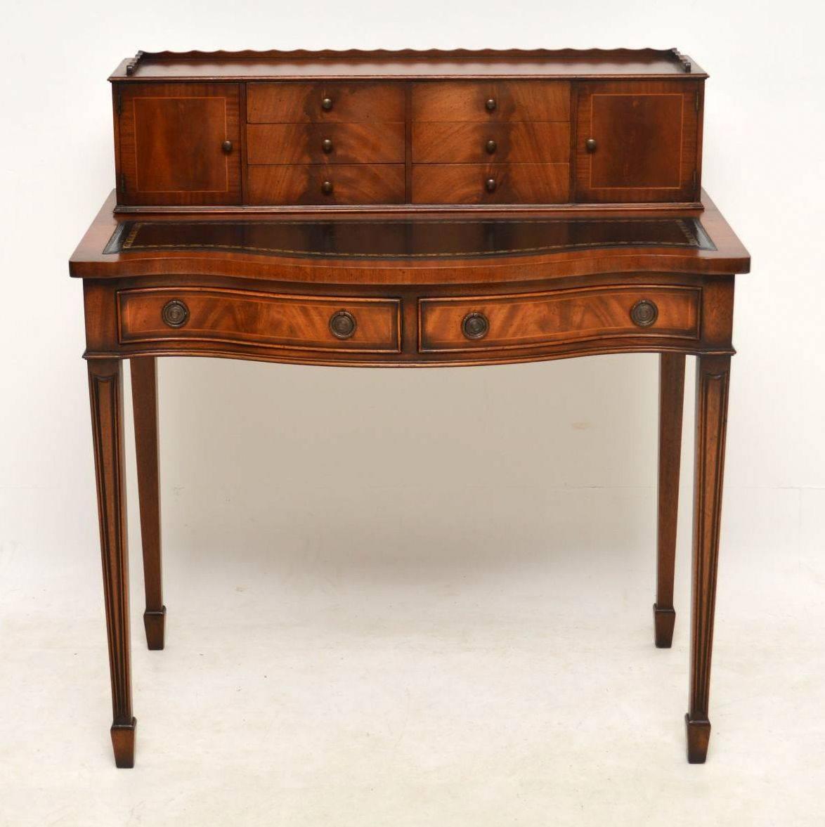 Very elegant antique Sheraton style writing table with some fine features, in good condition and dating from circa 1950s period. There are two banks of drawers and two cupboards with a shaped gallery above the tooled leather writing surface. Below