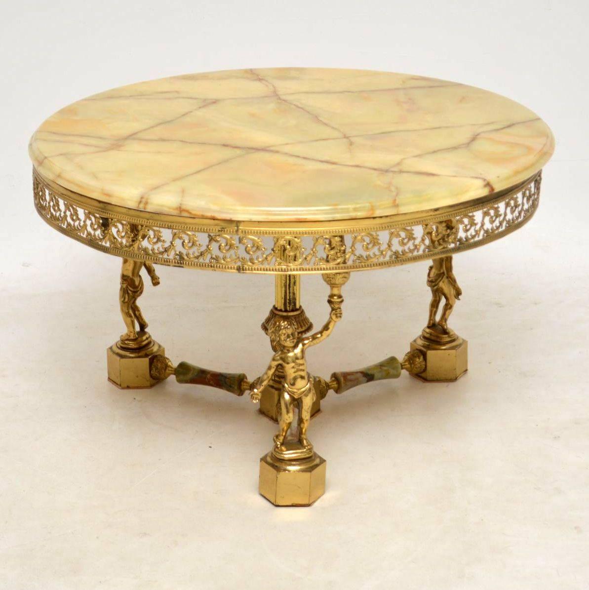 Antique circular onyx top brass coffee table in excellent condition and with some lovely features. it has some very intricate filigree work under the onyx top. The base consists of three cherubs holding up the top. There is a central column with