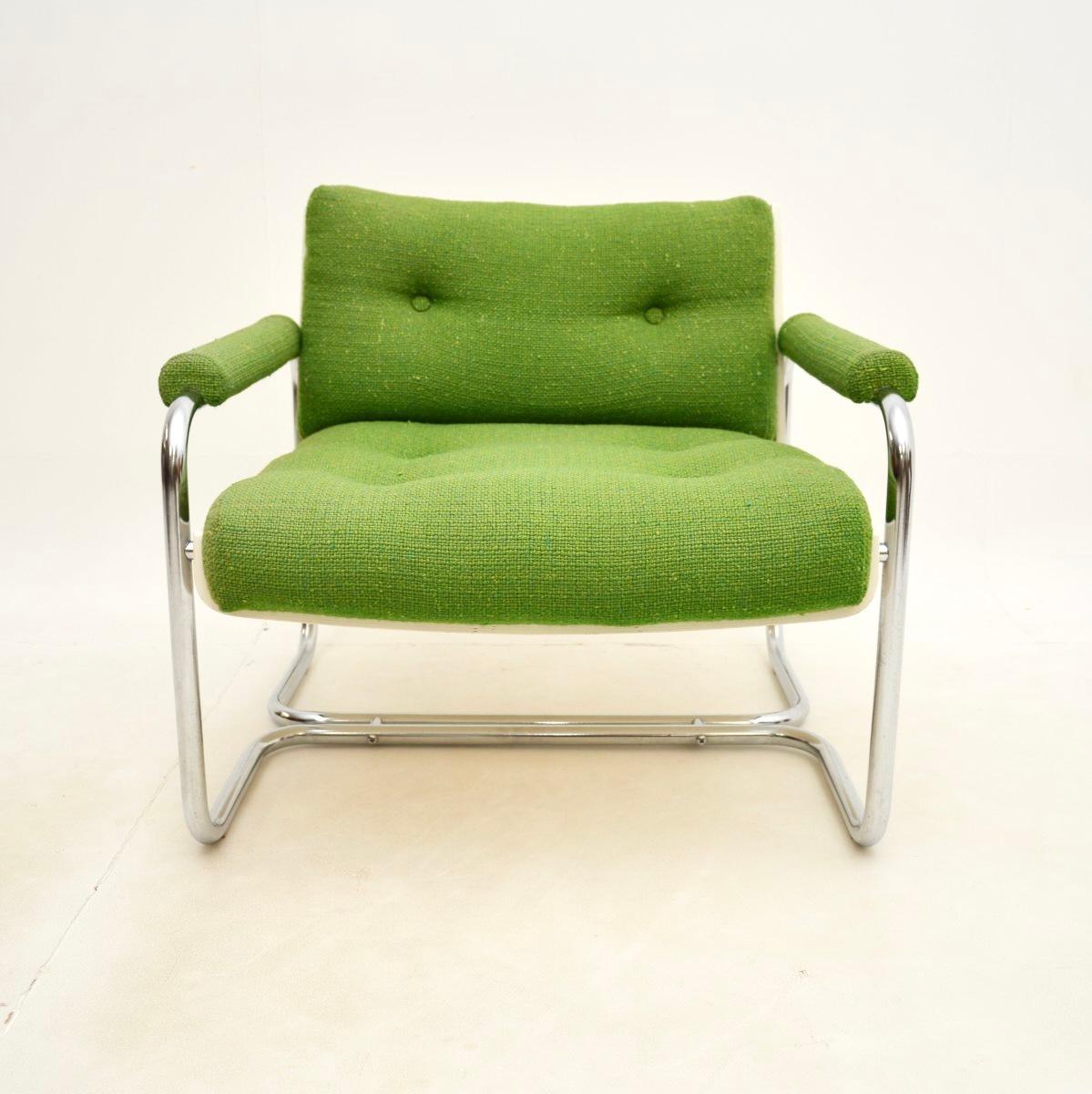 Un elegante e inusual sillón vintage de acero tubular con respaldo de concha de mediados de siglo. Se fabricó en Inglaterra y data aproximadamente de los años 60-70.

La calidad es asombrosa, la tapicería de lana verde es original y está colocada en