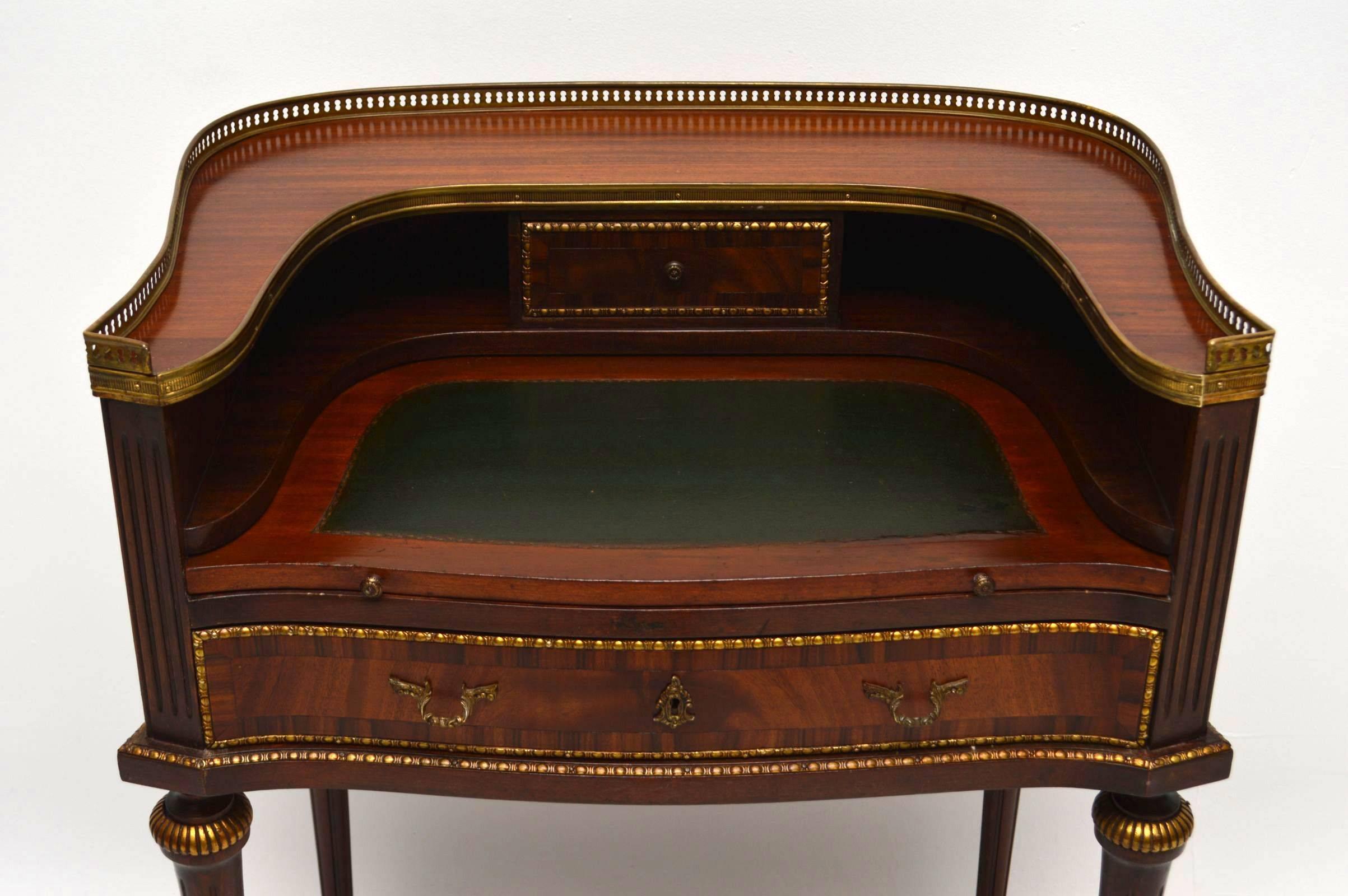 Antique French mahogany writing table with an interestingly shaped top section that runs all the way around it. It has a pierced gilt metal top gallery and gilt metal mounts handles and feet. This desk has many nice features, including reeded