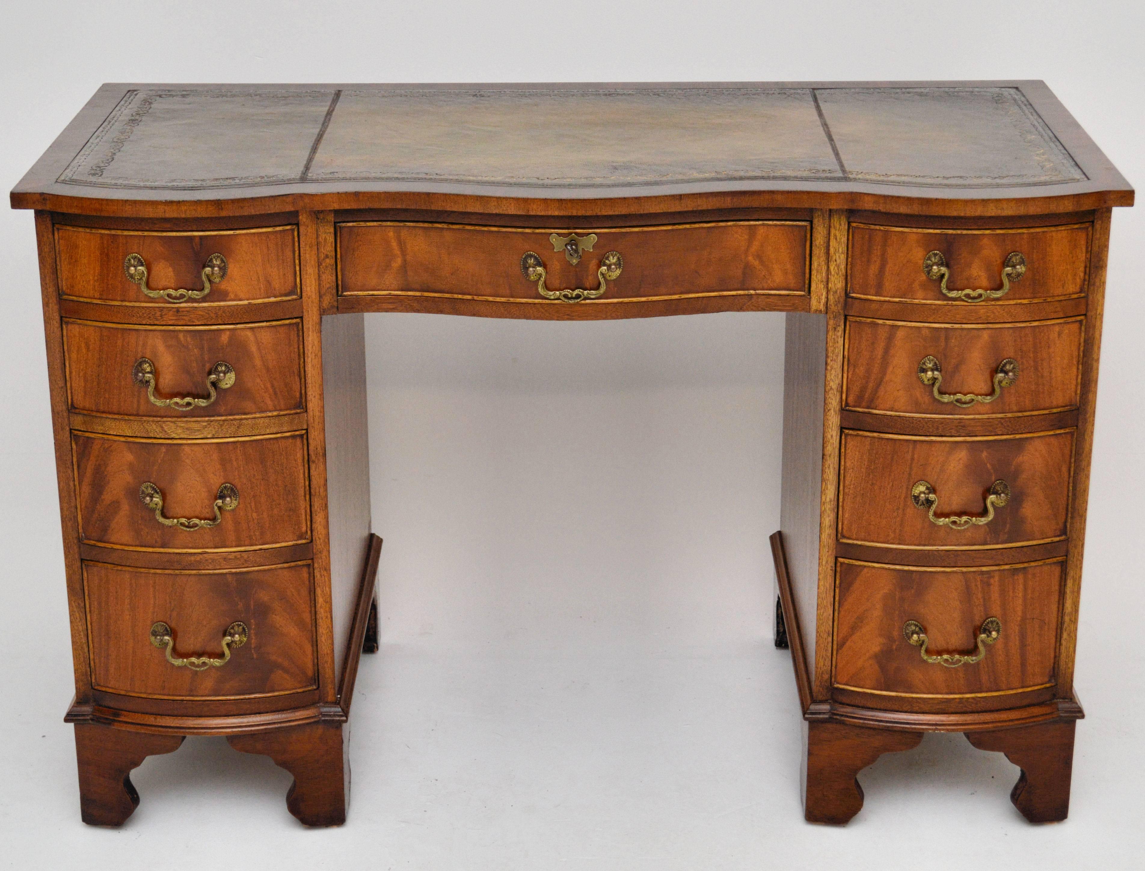 Good quality antique Georgian style flame mahogany desk, with a double serpentine shaped front and a polished flame mahogany back. It has a lovely faded green tooled leather writing surface, one-drawer in the middle and four more either side of the