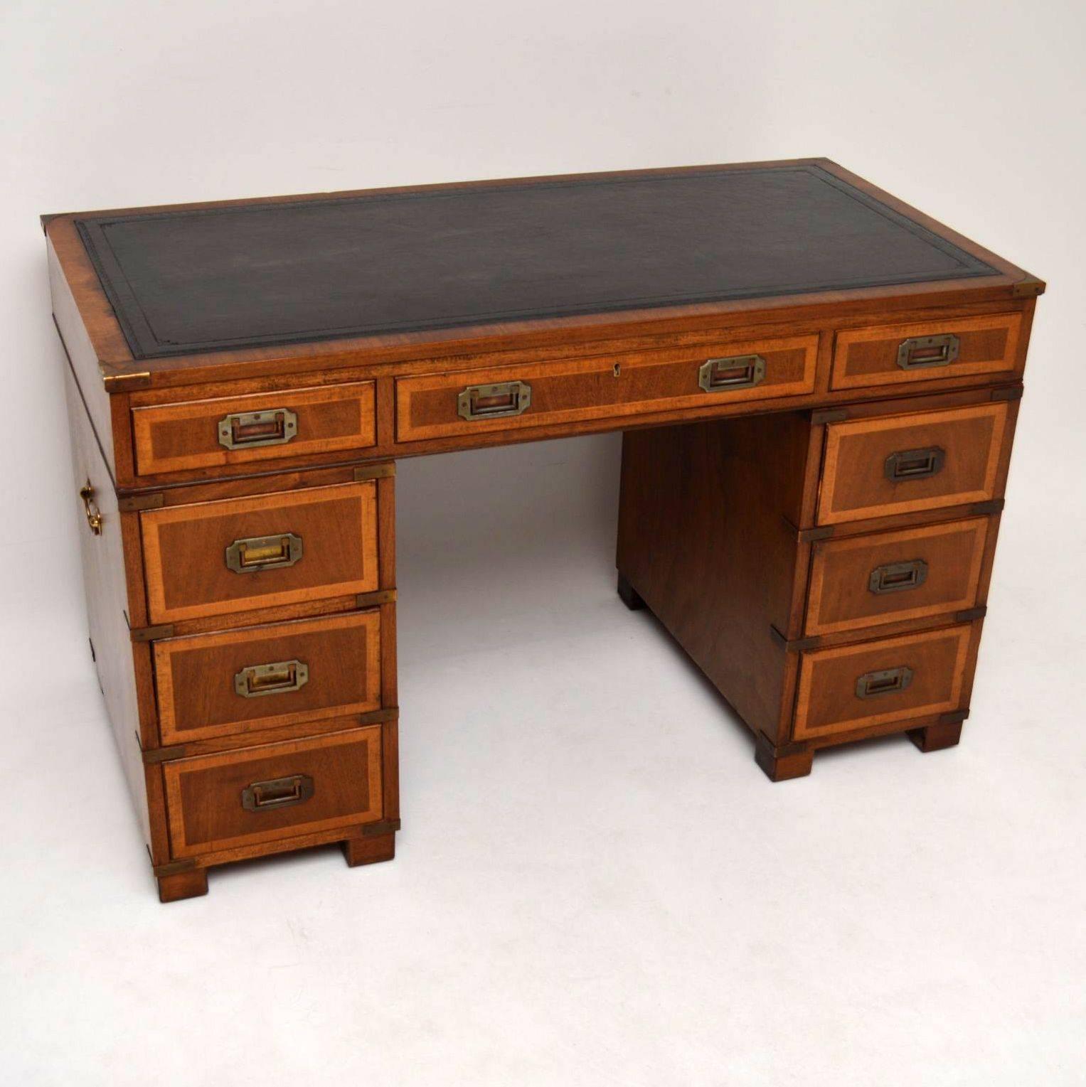 This antique mahogany 'Campaign' pedestal desk is in lovely condition and has loads of character. It has a hand-dyed tooled leather writing surface, brass carrying handles on the sides and brass corner edges. The original handles on the drawers are