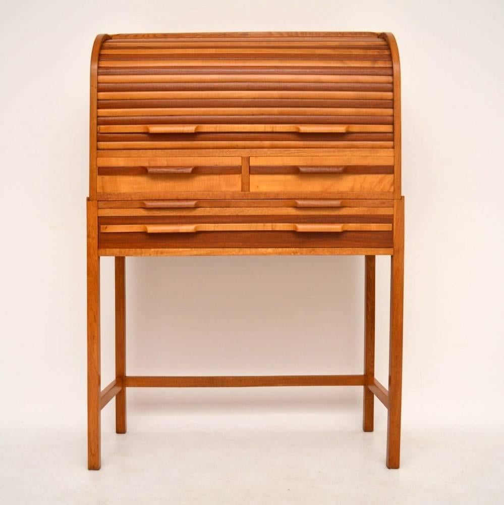 An incredible and unusual roll top writing bureau from the 1950s, this is beautifully made from various woods. The rolling tambour is made from alternating strips of Satin Wood and Mahogany, the carcass and legs are made from oak. We have had this