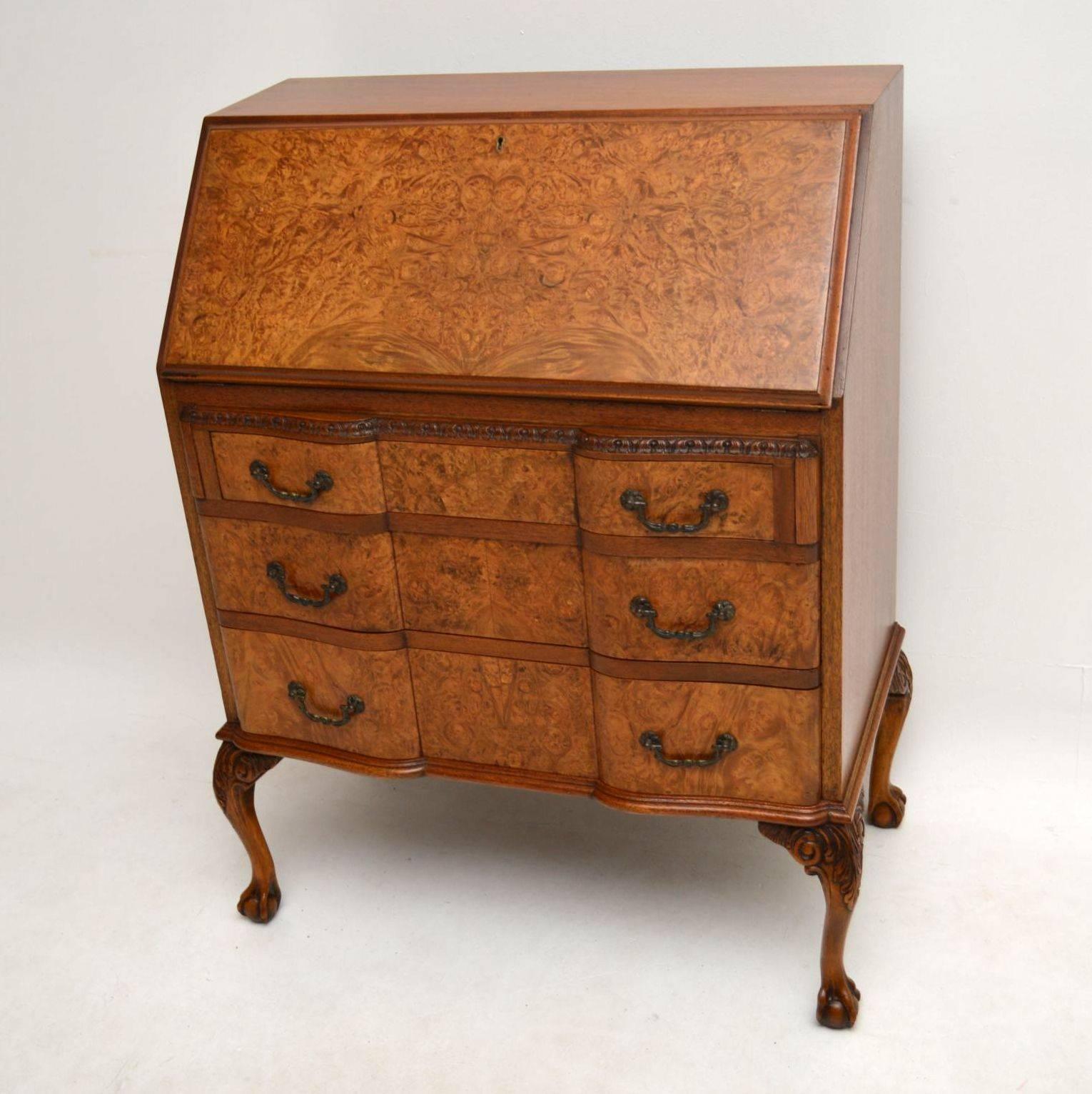 Good quality antique bureau with a well patterned burr walnut front and with figured walnut sides. It has fine carving just above the top drawer & on the tops of the solid walnut legs, which have claw & ball feet. The three shaped drawers are