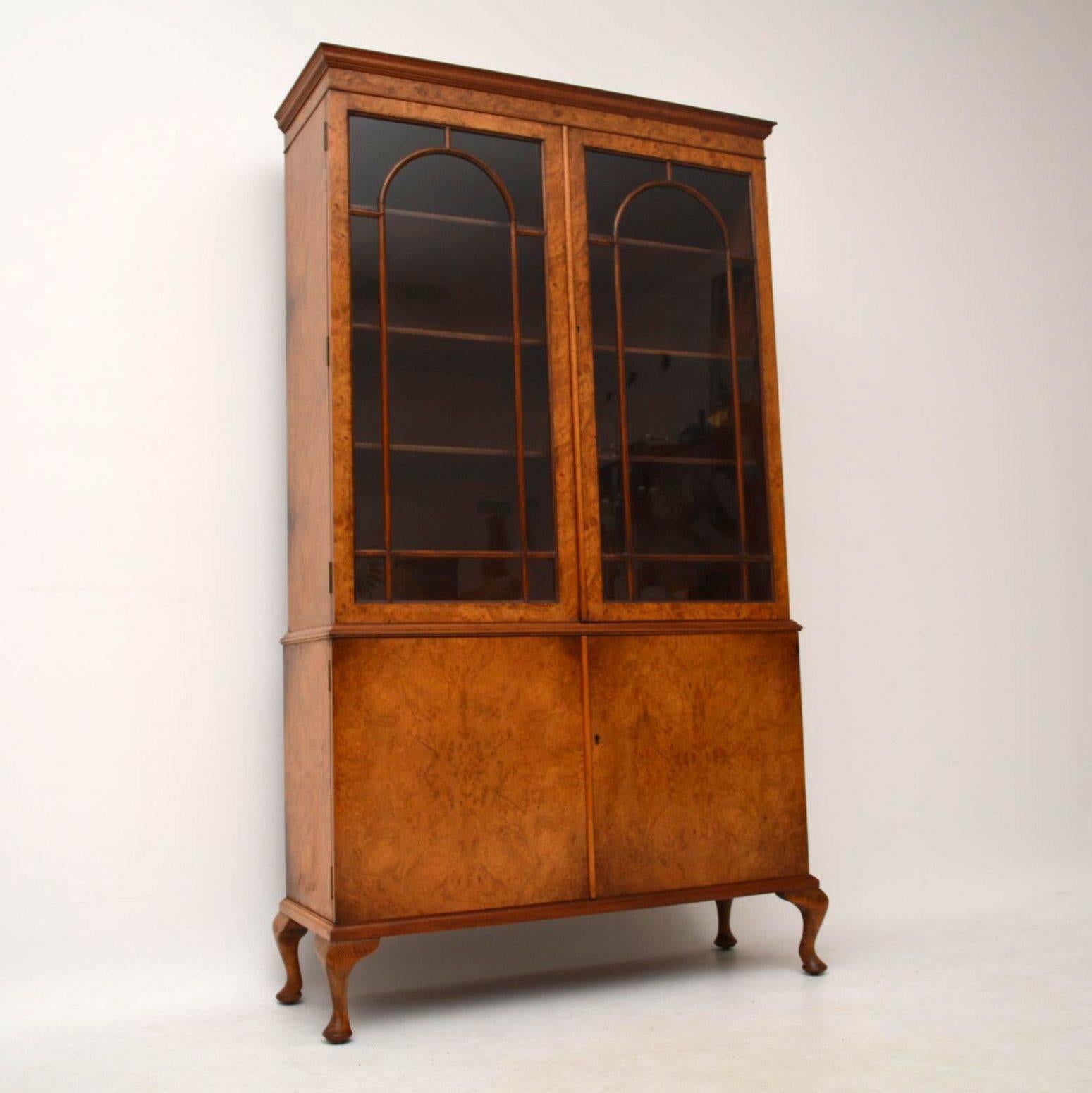 This large antique burr walnut bookcase has a lovely warm color and good figuring on the wood. The top section has astral-glazed doors and inside are four adjustable shelves. The bottom section has burr walnut cupboards with one shelf inside. This