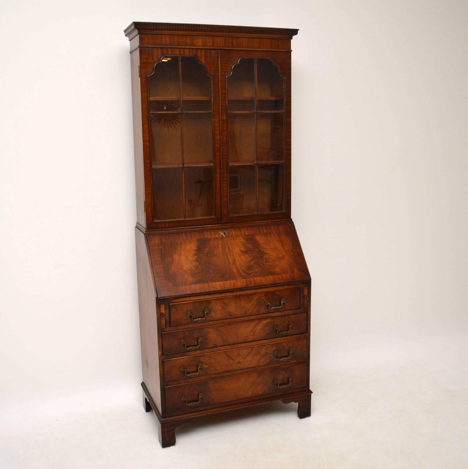 Antique Georgian style mahogany bureau bookcase in excellent condition and dating from around the 1950s period. It has double arched astral-glazed doors, with adjustable bookshelves inside. The writing section has a Fine array of small drawers, a