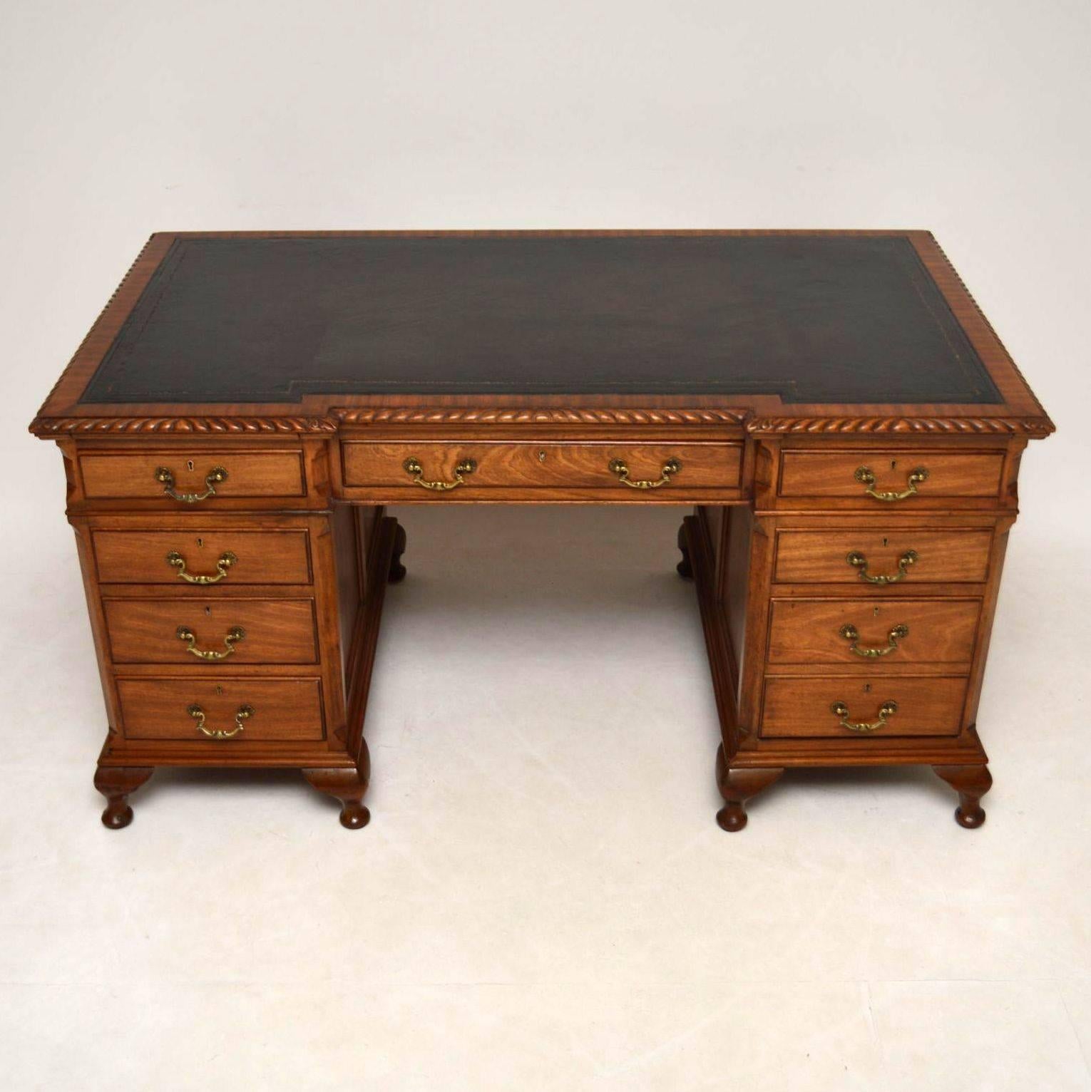 Large impressive antique mahogany pedestal desk with an inverted breakfront in good condition and dating from circa 1900-1910 period. It has a hand colored tooled leather writing surface, a gadrooned top edge, two slide out surfaces either side just