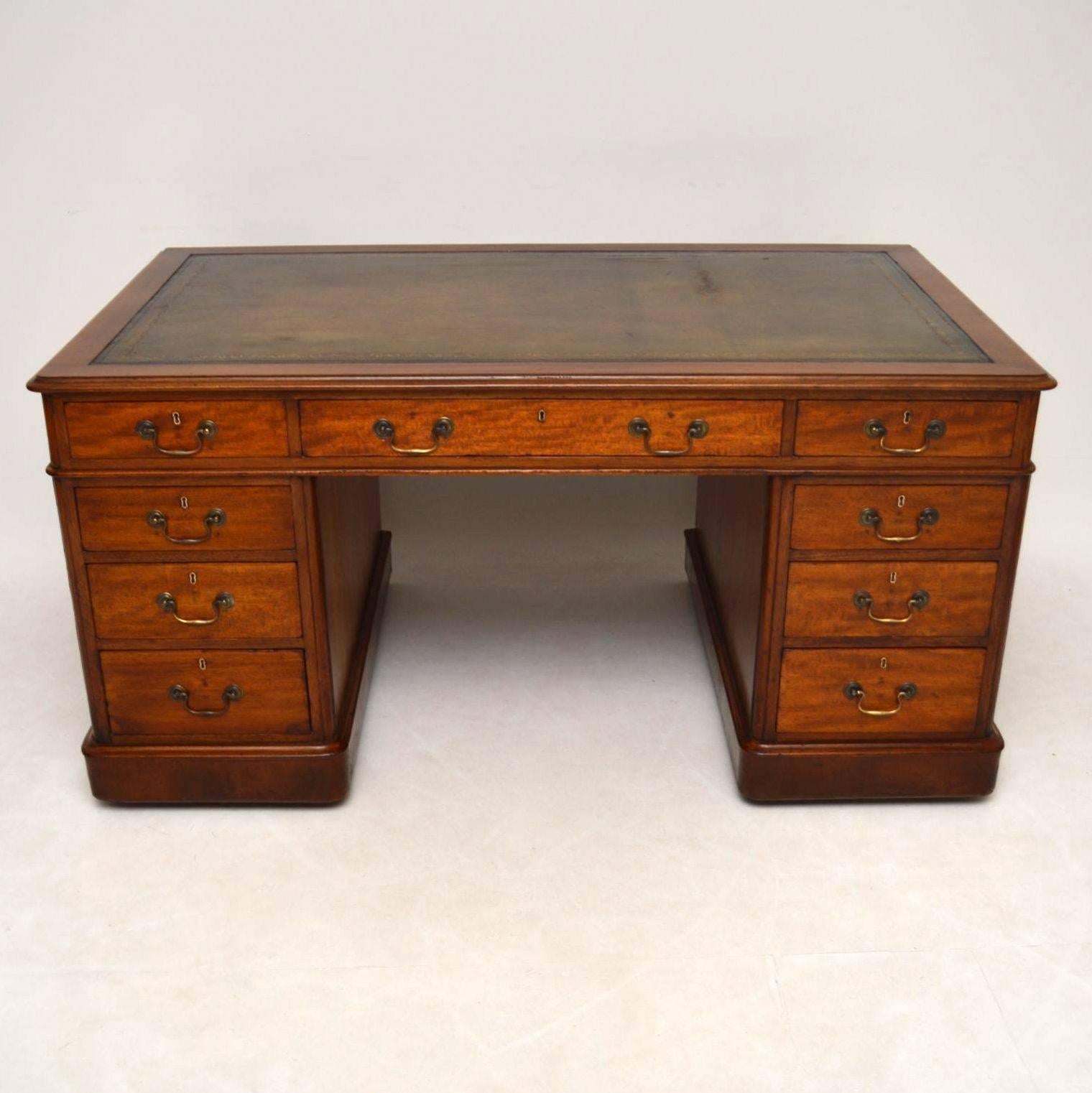 Large Victorian mahogany pedestal desk with a tooled leather writing surface and a generously wide kneehole area. It has rounded corners, graduated drawers with antique brass handles, polished panelled backs and sits on plinth bases with concealed
