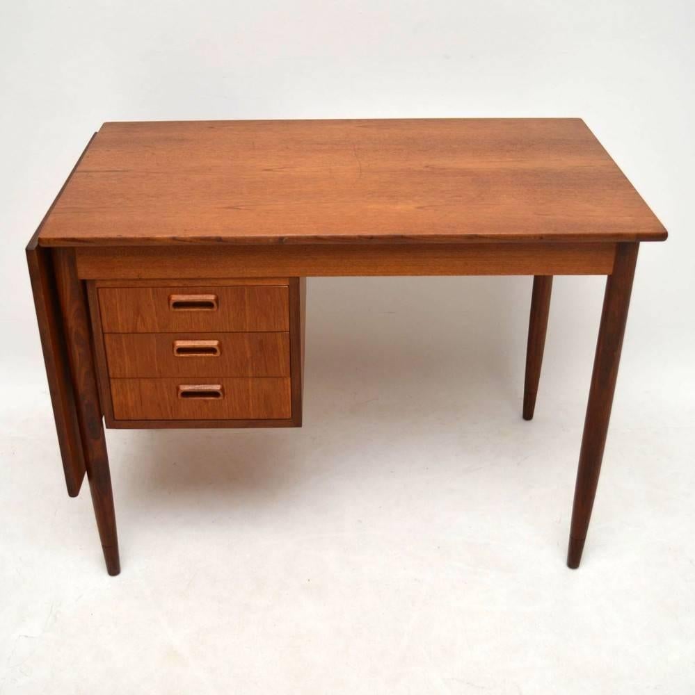 A stylish and very practical Teak desk, this was designed by the famous Danish designer Arne Vodder. It was made in Finland by Asko, this dates from around the 1960s. This has a drop leaf which when lifted extends the surface area of the desk top.