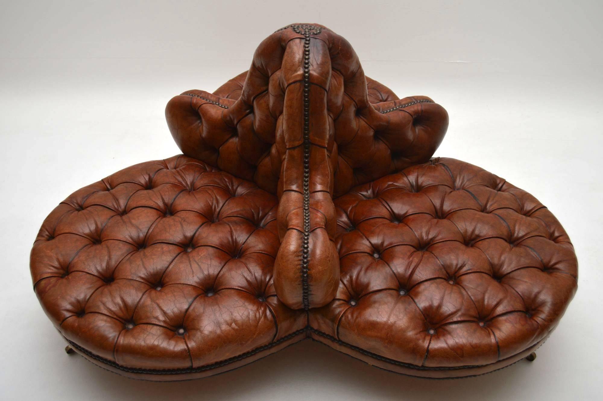 This antique Victorian deep buttoned leather conversation sofa is in good original condition. The leather has a wonderful tan color and is naturally distressed, with normal fading that would be expected for a piece of this age. There are no splits,