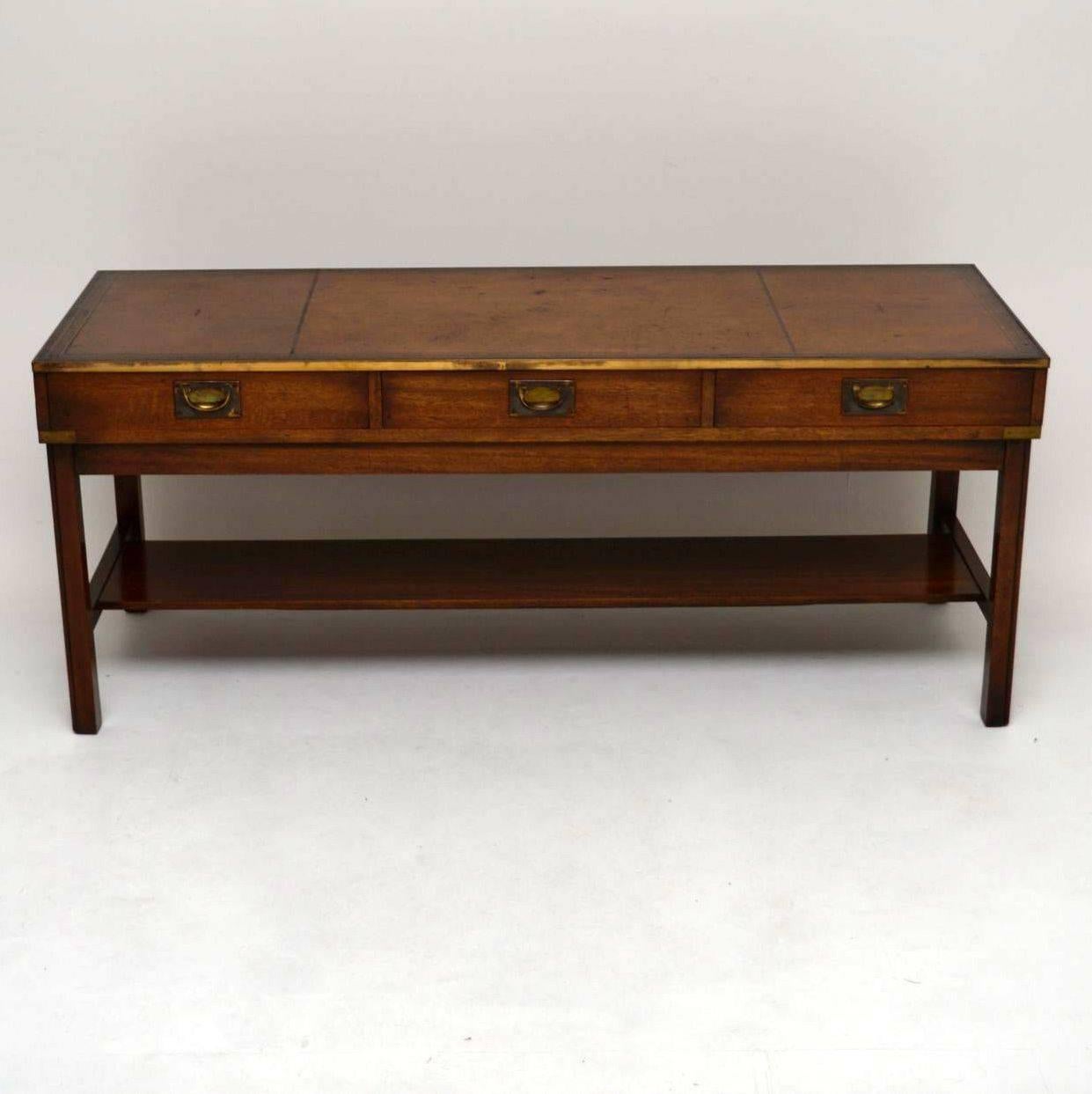 It's hard to find antique coffee tables and even harder to find large ones. This coffee table is great looking and is Campaign style, with an original leather top, brass corner pieces, three drawers with brass military handles and a brass trim all