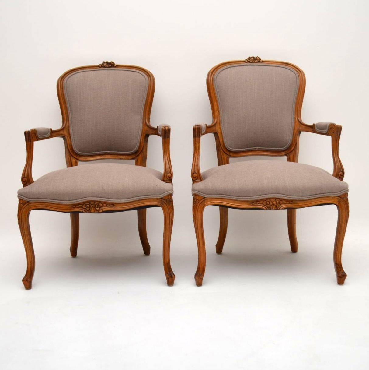 Pair of antique carved walnut French salon armchairs in excellent condition and newly re-upholstered. The frames are finely carved and have a great shape. The neutral colored fabric is double piped on the edges. I would date them to around the