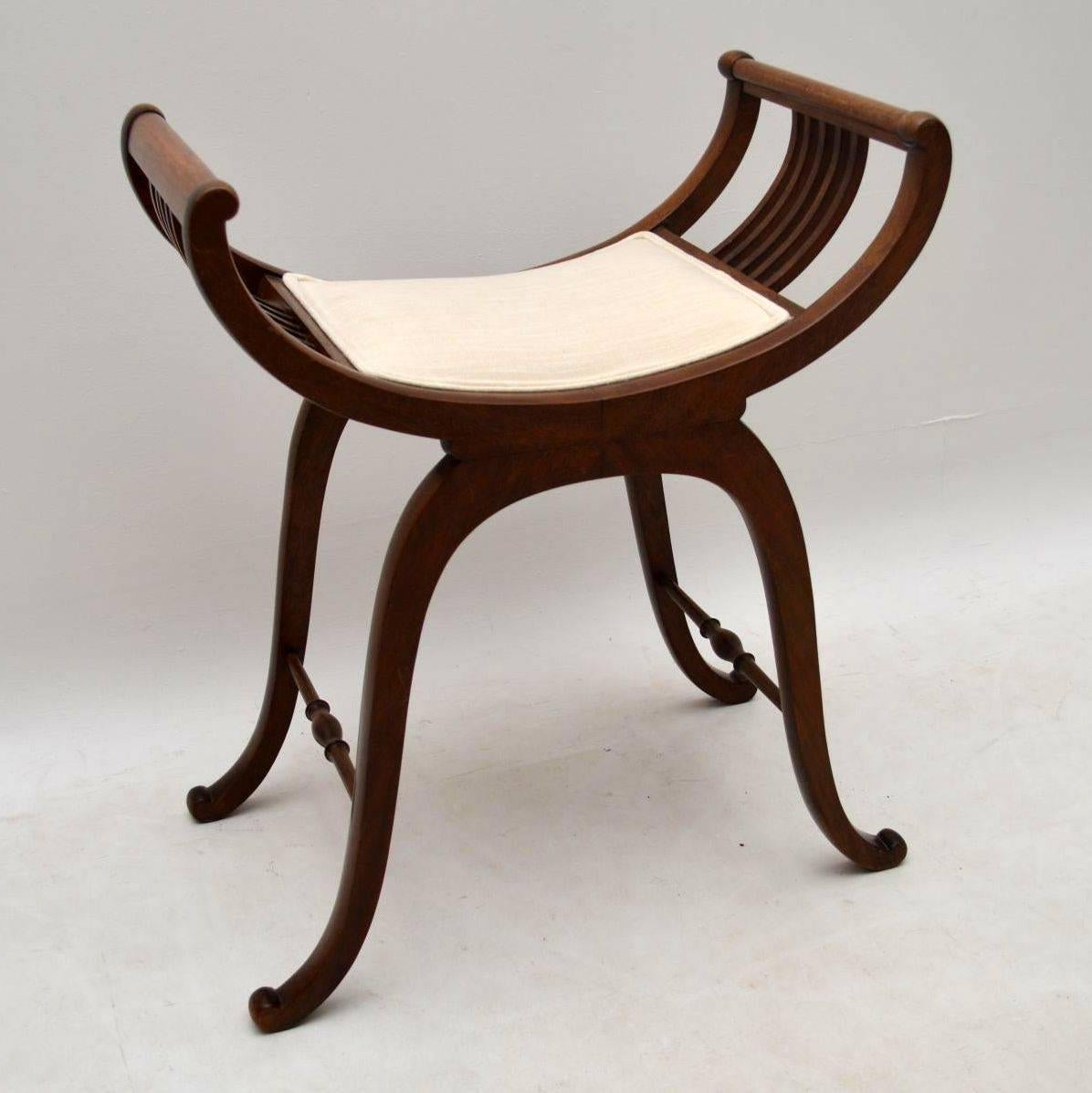 This antique Edwardian mahogany stool is very elegant and has a beautiful design. The top has a gondola shape with a newly upholstered seat and curved struts. The legs are well shaped too and have turned cross stretchers which help give it more