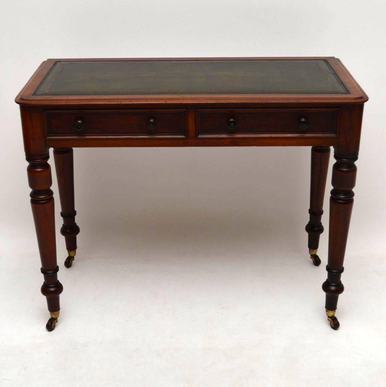 Antique early Victorian leather top mahogany writing table in good condition and dating from the 1840s-1860s period. It has a tooled leather writing surface, two drawers with original turned bun handles and well turned legs with brass capped