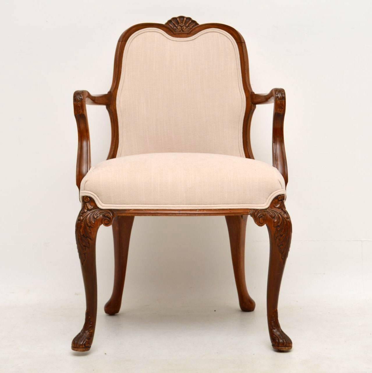 This solid walnut upholstered open armchair is in good condition and dates from the 1910-20’s period. It’s very much Queen Anne design with the typical carvings & the shepherds crook arms. There are shell carvings on the tops of the solid walnut