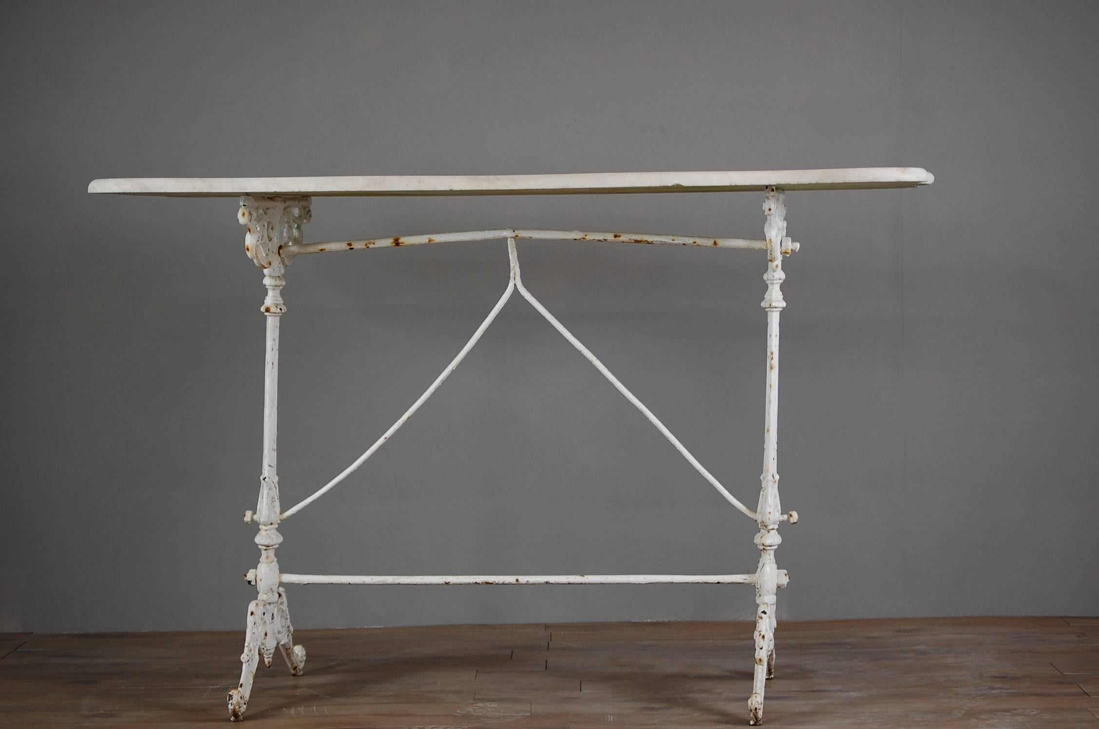 Early 20th century English cast iron, marble top orangery table. Detail intricate casting of the base with layers of old chippy paint. The marble top is drilled to secure in place on the base. The wavy edged marble is wonderfully decorative, with a
