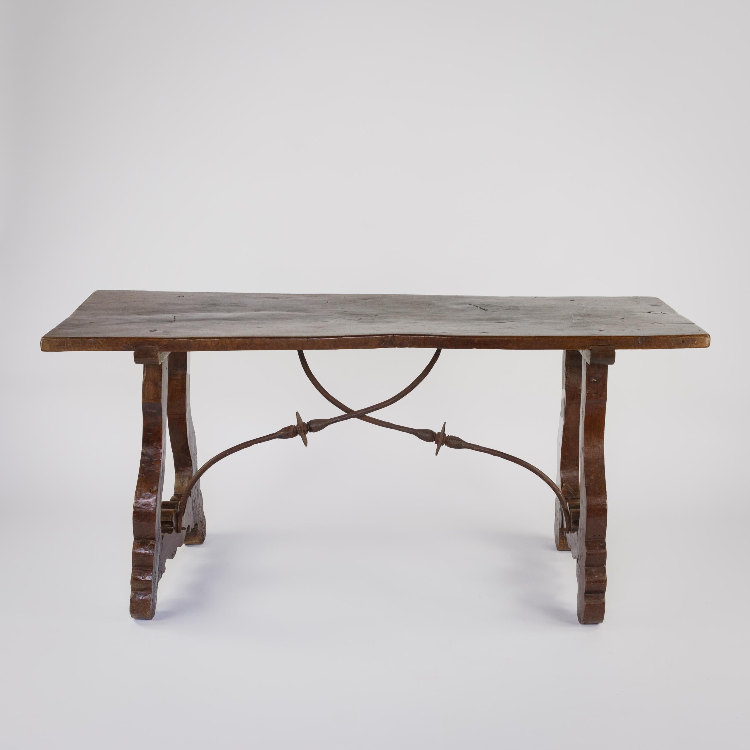 Table à une planche en noyer avec des supports sculptés ornés et des châssis en fer forgé. Bon plateau épais, avec une belle patine. Espagne, vers 1820.