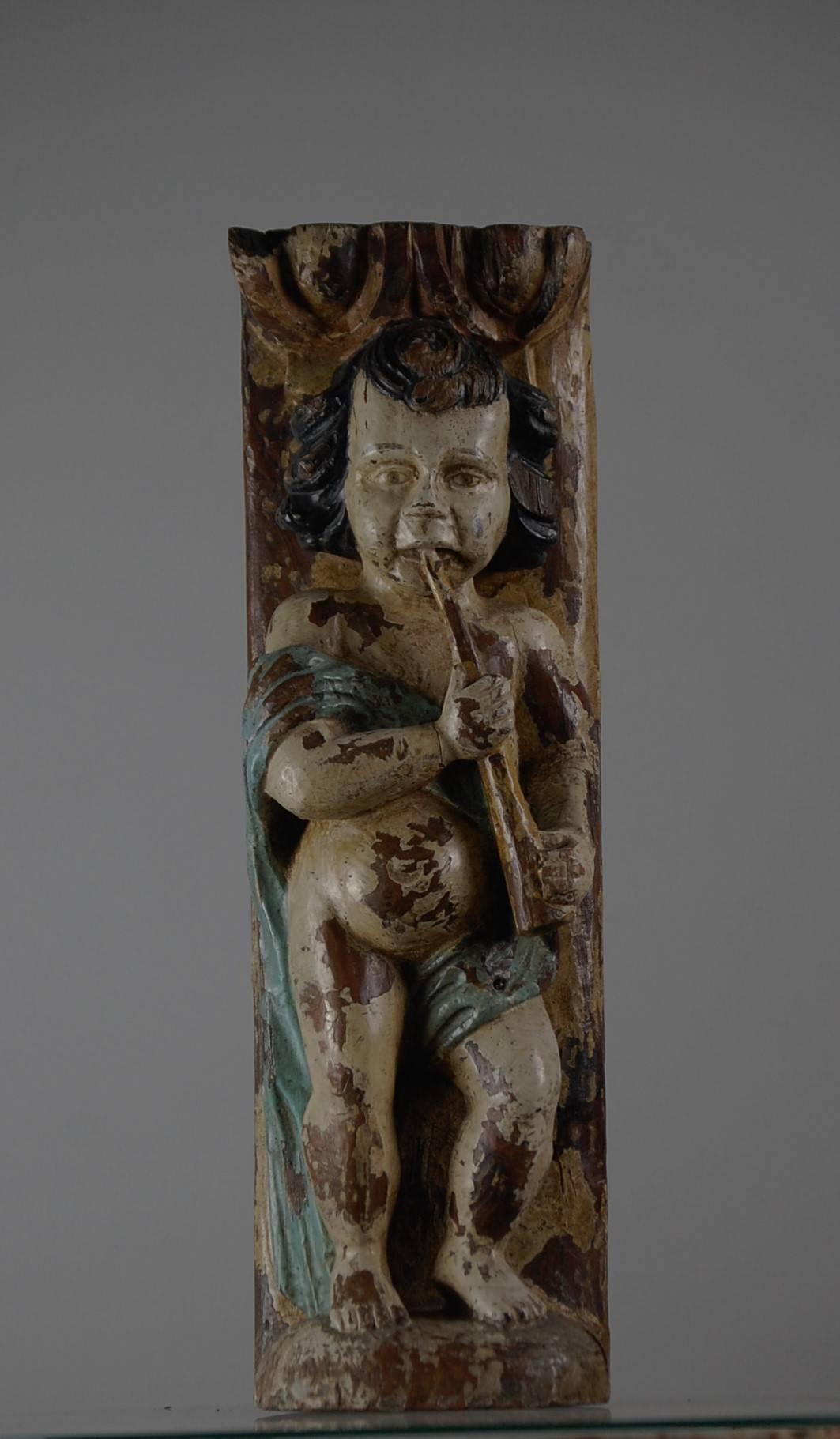 A wonderful carved wood cherub or putti playing a trumpet, distressed original polychrome finish. Believed to be a fragment from a French fairground organ, circa 1860.