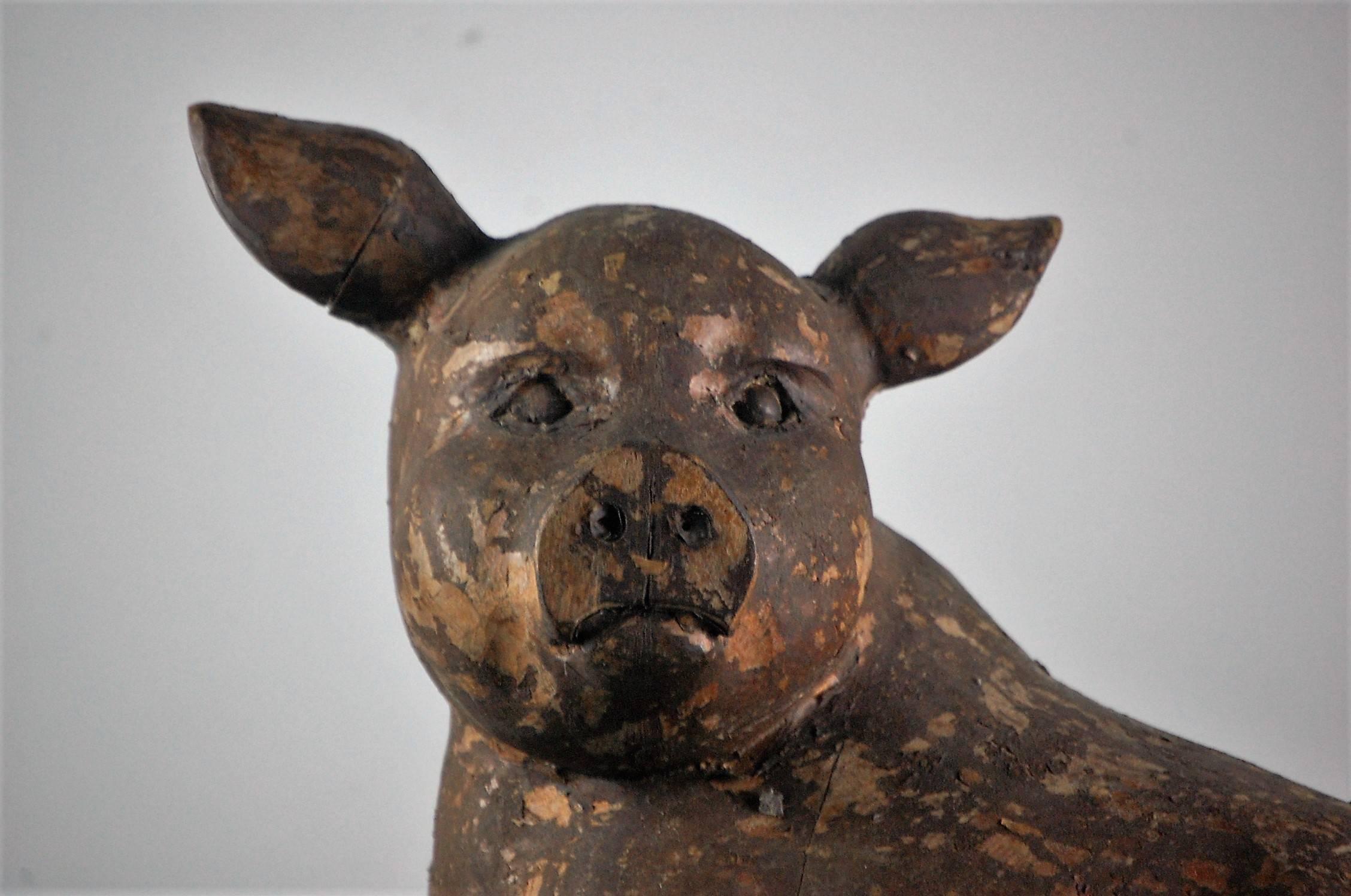 A wonderfully expressive carved wood pig, used as a Butchers trade sign papier mâché mold. It has obtained a beautiful dry finished patination with paper remnants from its working life. English, circa 1920, he has a wonderful old repair to a drying