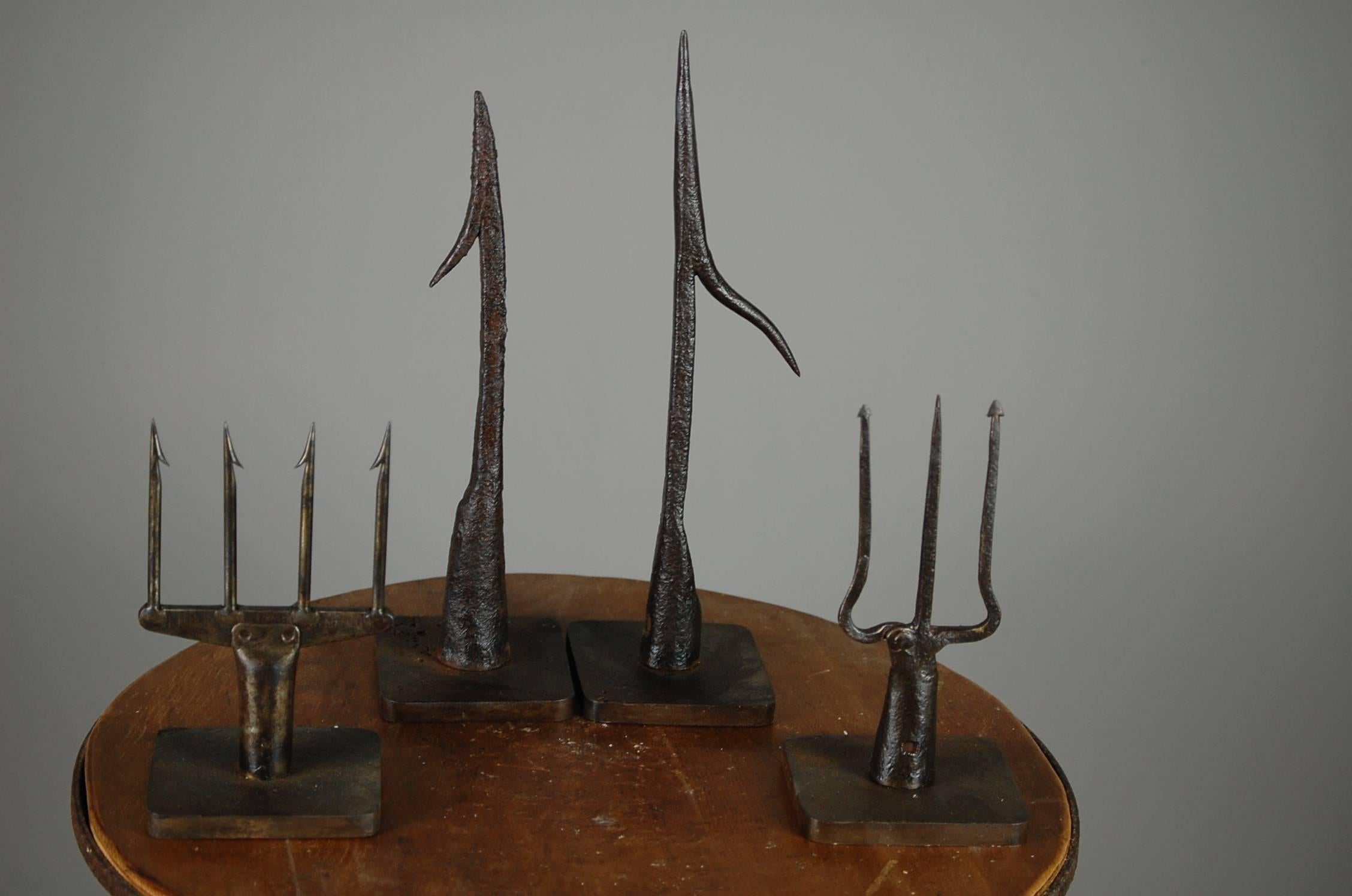 A collection of (4) Fine wrought iron fish spears, the trident being 18th century and the others two being 19th century. Burnished finish mounted on individual metal stands. Price is for the collection of four. English. Measurement is for largest