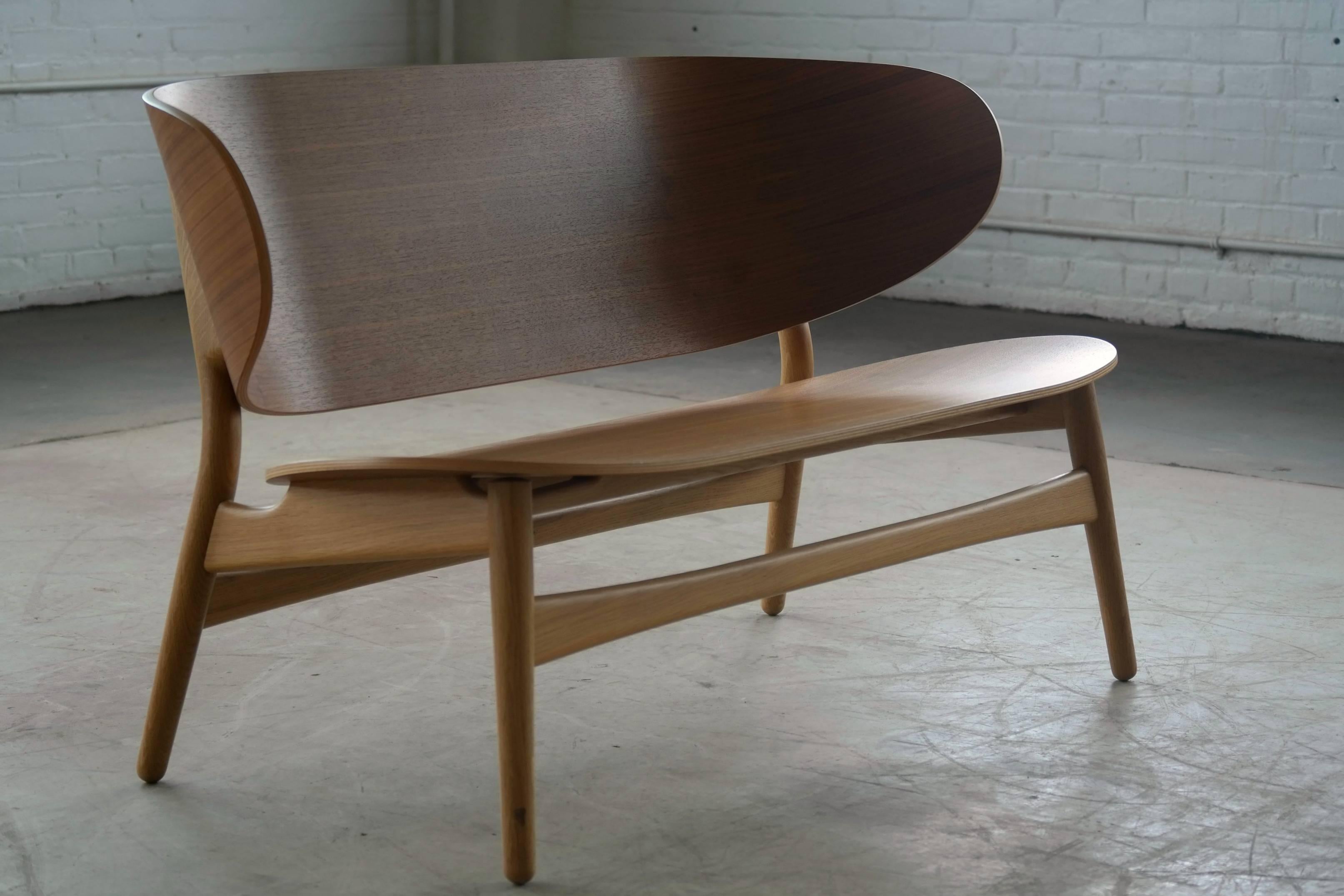 Beautiful shell bench originally designed by Hans Wegner in 1948 and re-issued by GETAMA for which Hans Wegner was a house architect in 2015.

Bent walnut ply over a base of soap treated solid oak. This piece was used as display and could have