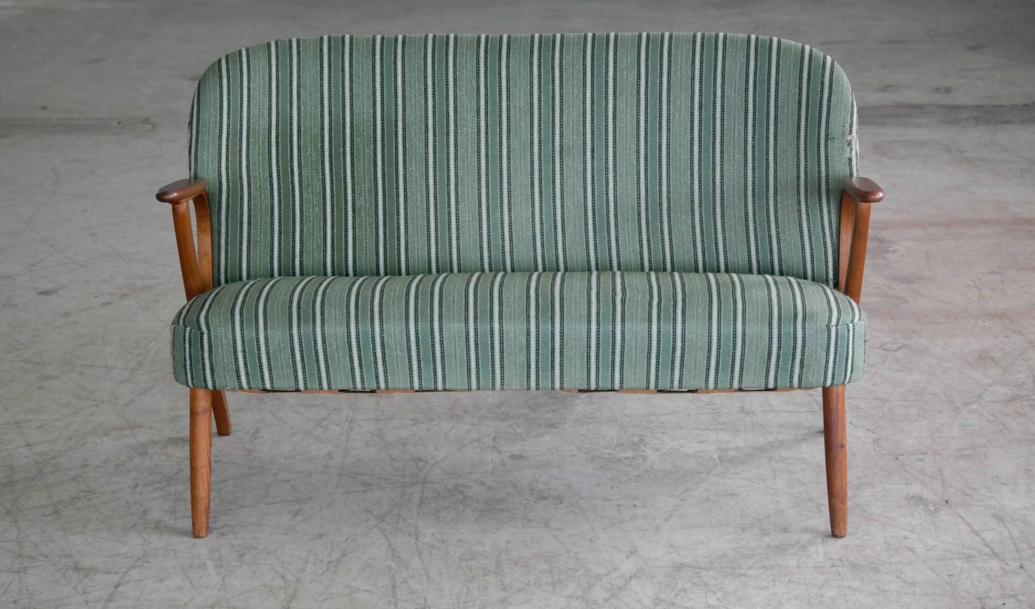Beautiful and elegant small 1950s Danish sofa with legs and armrests in teak. The high quality woodwork and design is very much in the style of Arne Hovmand Olsen and N.A. Jorgensen (Bramin Mobler) but it is unmarked and a rare piece and we cannot