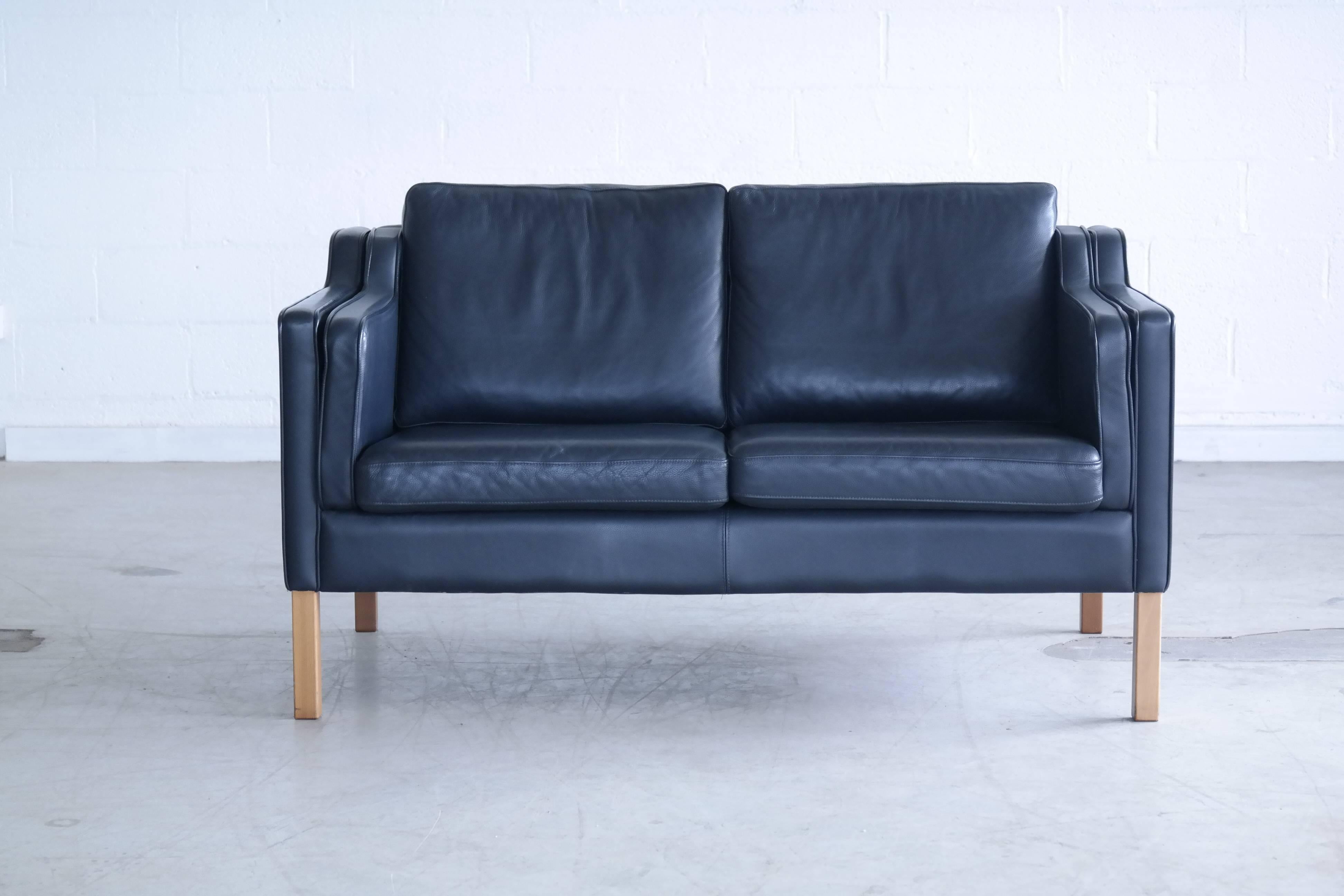 Very elegant and comfortable Classic Børge Mogensen style sofa model 2212 in Dark navy blue leather by Stouby Polsterfabrik of Denmark. High quality leather over a beech wood frame and legs. Cushions are top filled with down. Nice worn-in quality
