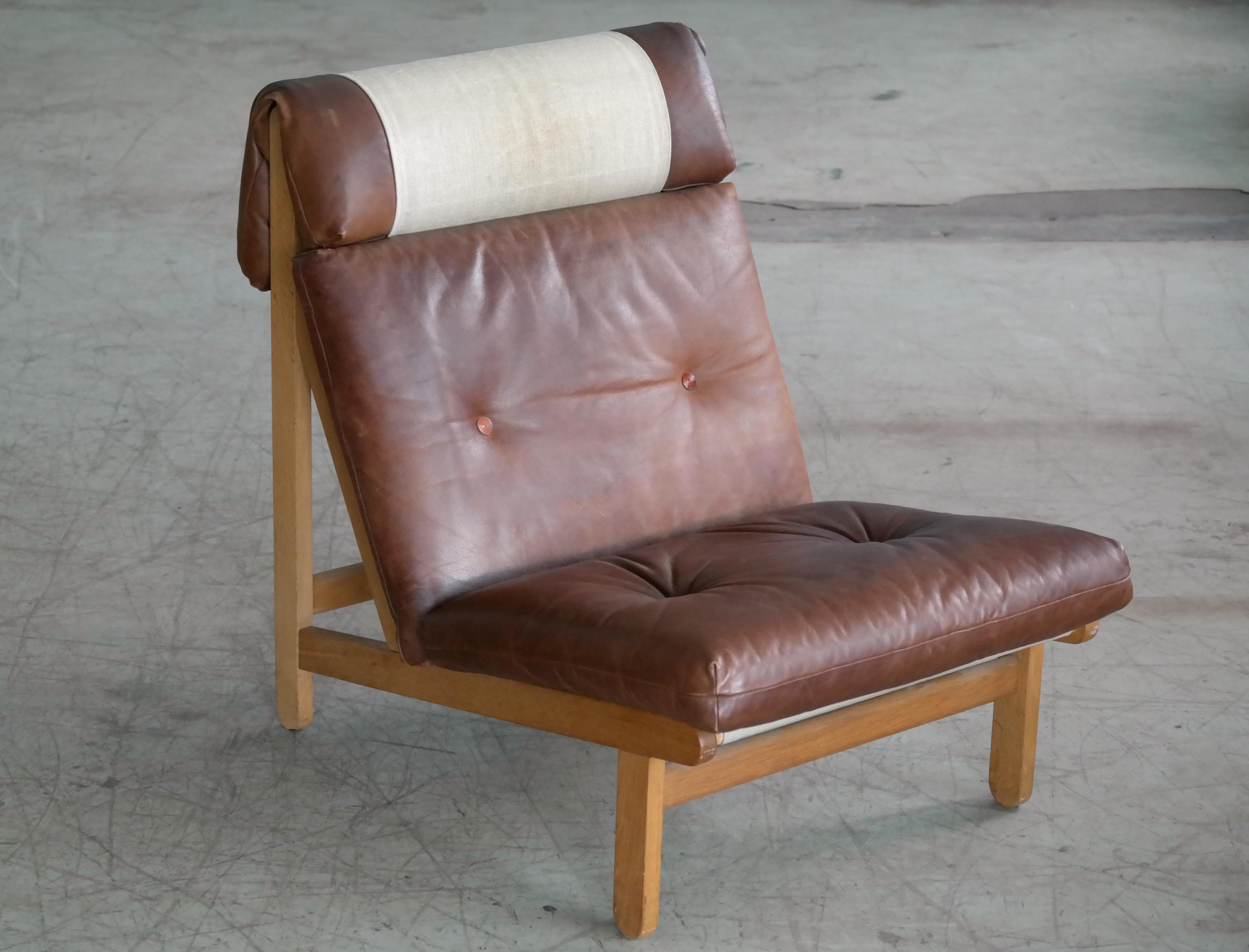 Rare and very sought after easy lounge chair designed by Bernt Petersen for Schiang Furniture of Denmark in 1966. Oak frame with loose cushions in seat and back upholstered with brown leather fitted with buttons. Neckrest and seat stretched with