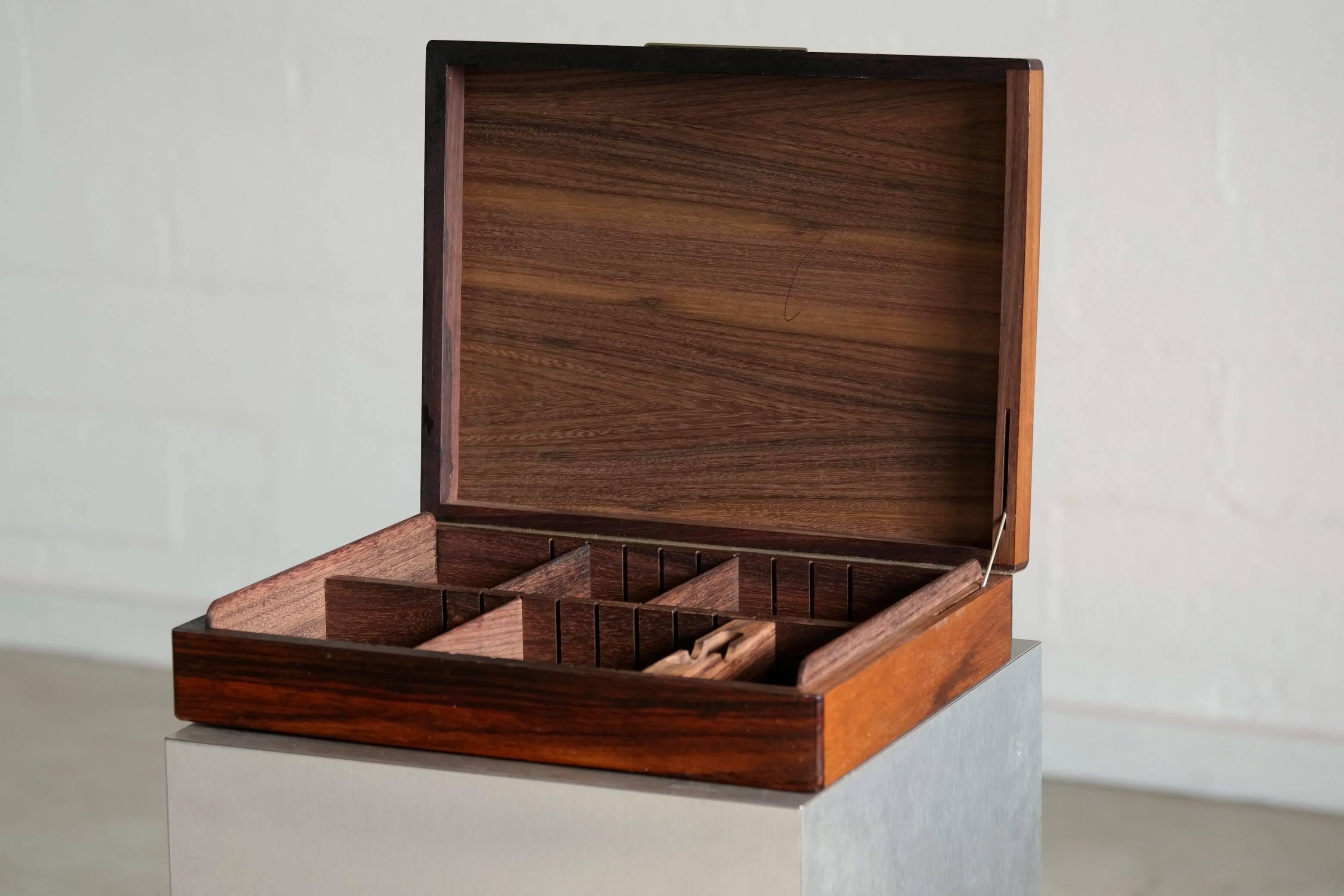 A beautifully constructed cigar box of rosewood richly grained Brazilian rosewood. Has several adjustable inner compartments and room for cutter which is present as well as a lighter.