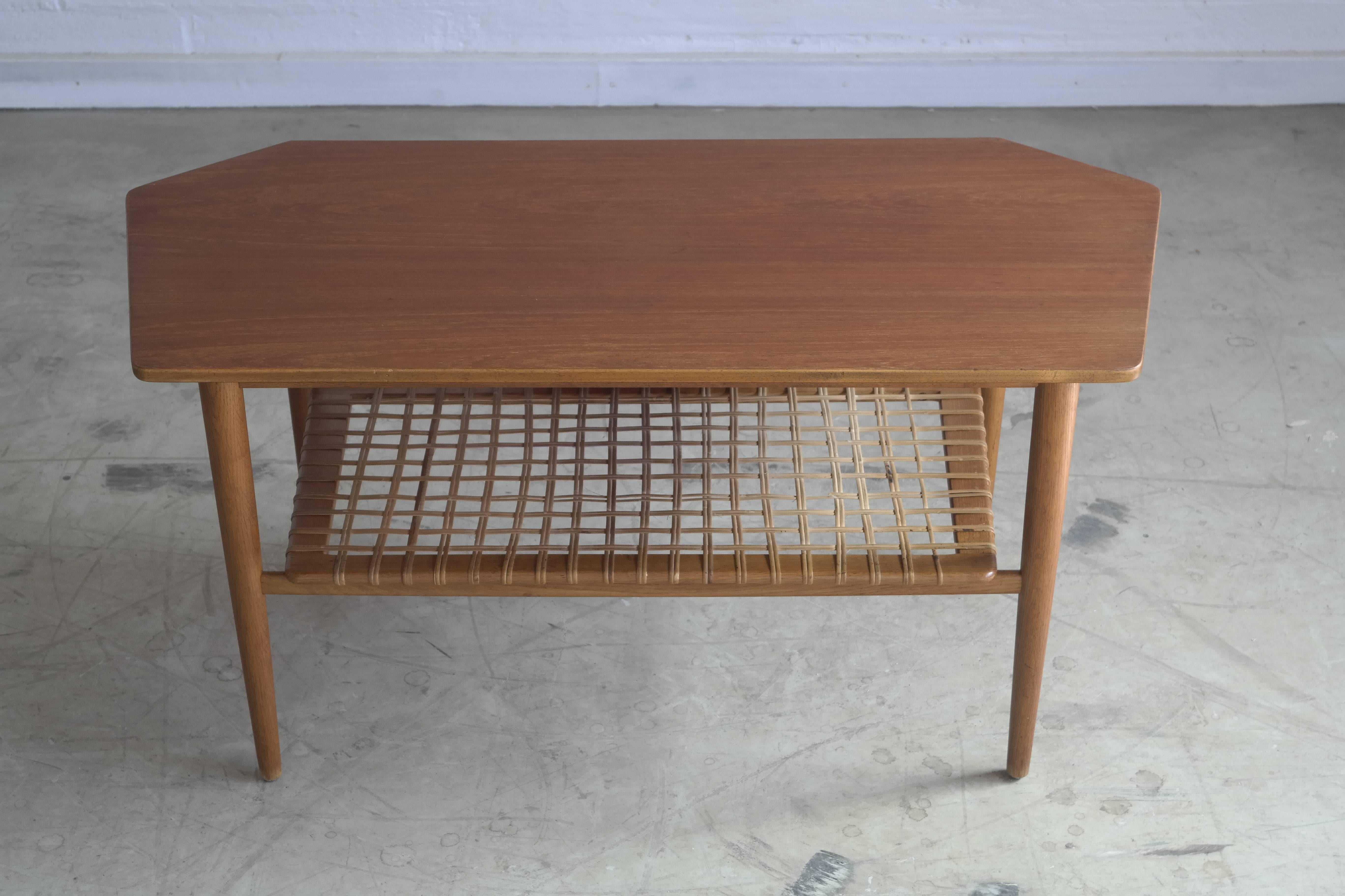 High quality asymmetrical Danish coffee table with extension leaf and nice cane magazine shelf. Unknown designer and maker but very interesting design that together with the quality execution and great condition makes for a good investment.