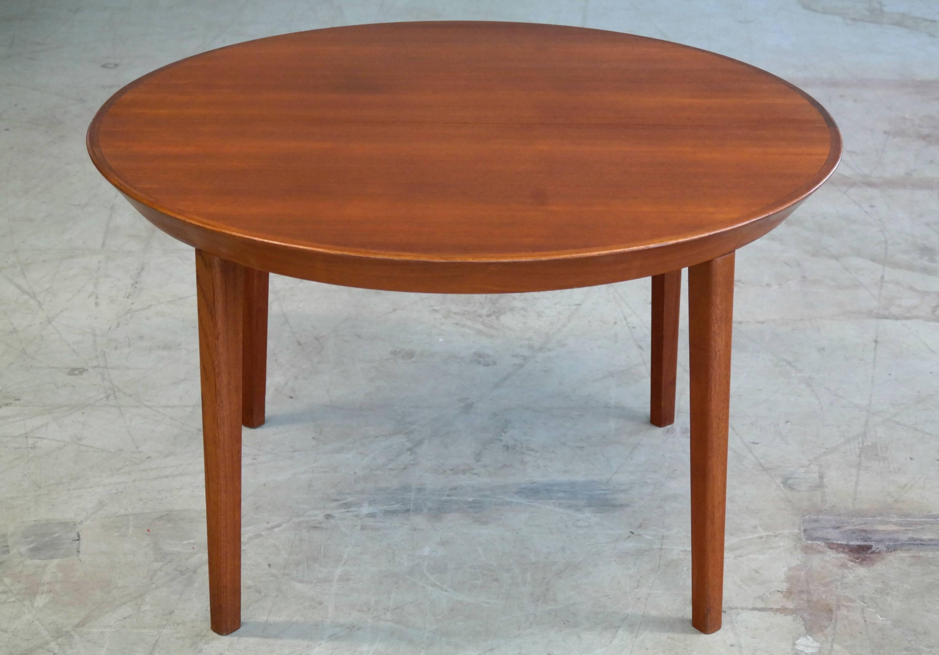 All restored very beautiful round dining table with beveled edges greatly designed by Ole Hald for Gudme Møbelfabrik. Superb quality and excellent condition.

Measures 48 inches in diameter with two extensions that together can make the table a