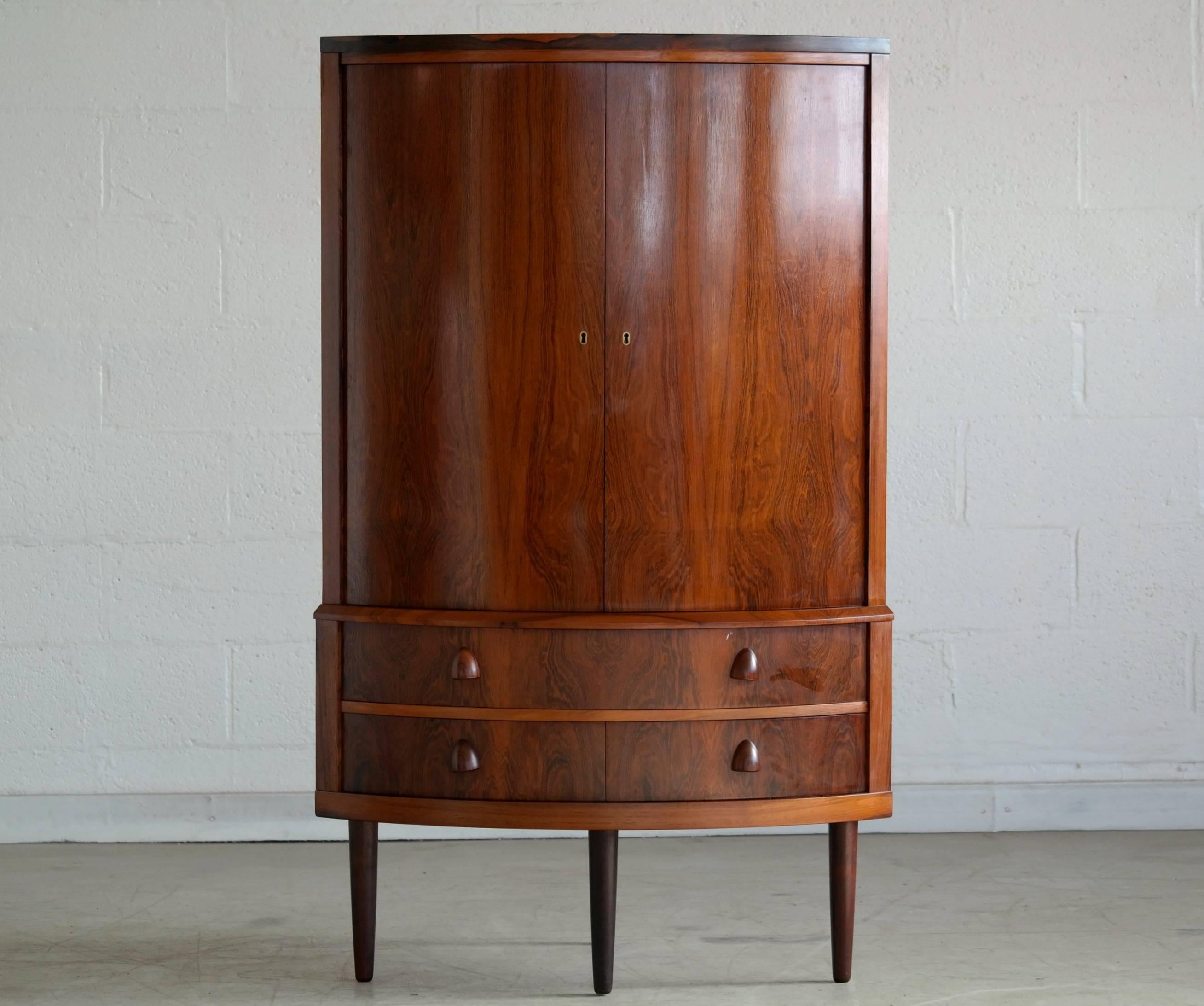 Fantastic rosewood corner cabinet attributed to Frode Holm. Rosewood veneer with beautiful grain. Solid edges and carved pulls. Elegant yet sturdy construction. High quality piece.