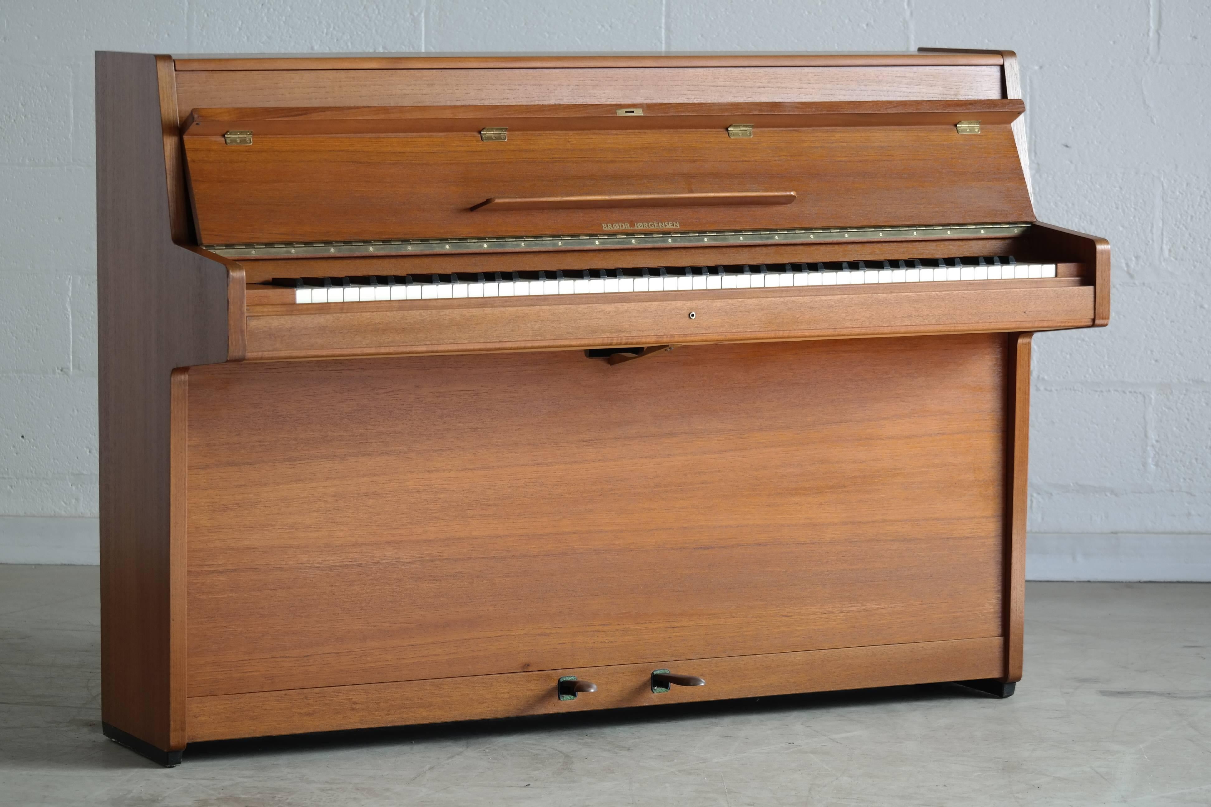 Great and well sounding Mid-Century piano in teak by Brødr. Jørgensen (Jorgensen Bros). Brødr. Jørgensen was a Danish piano manufacturer founded in 1913 closing its doors in 1978. Their pianos remain sought after based on their sound and high build